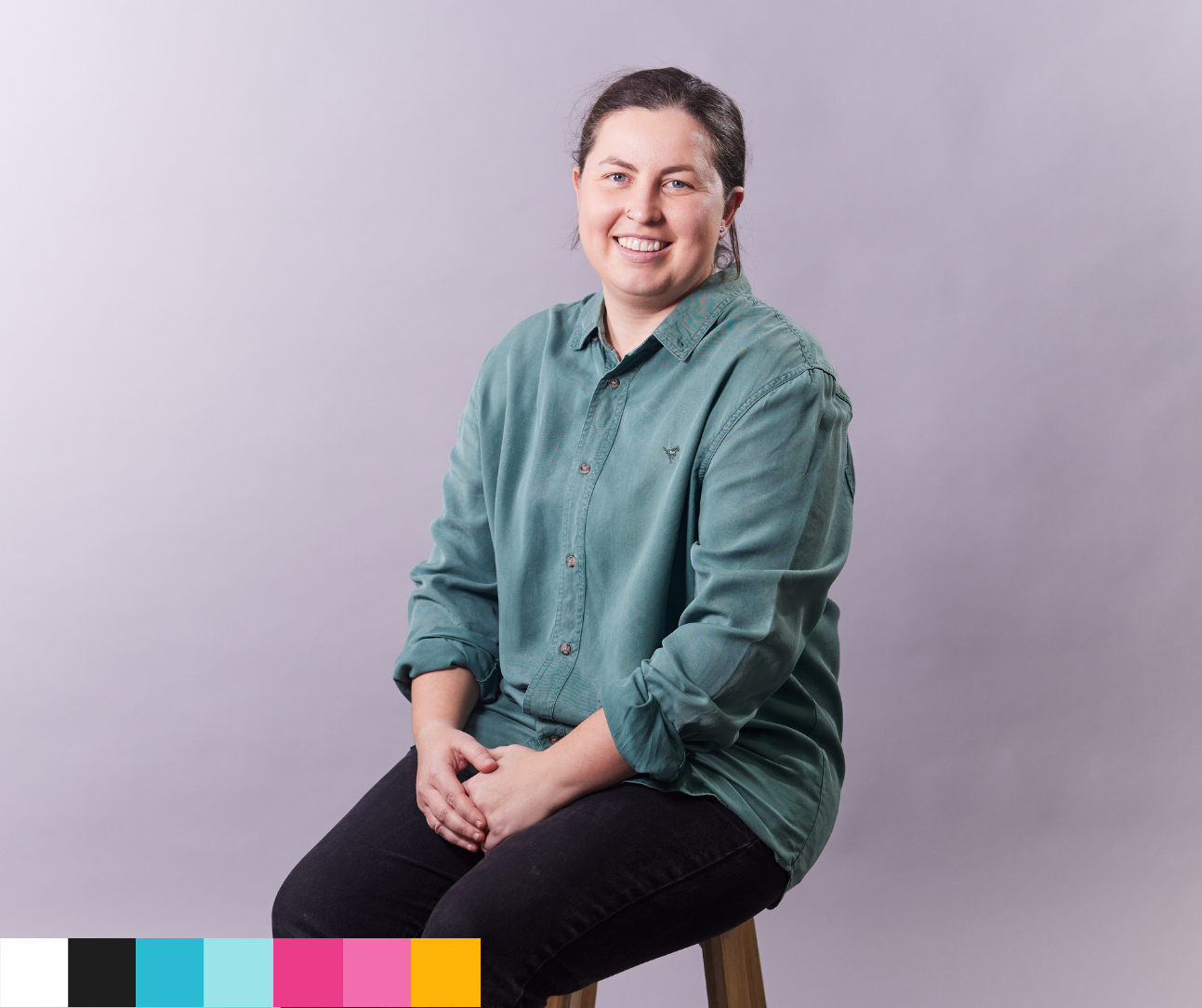 Person wearing a green shirt sitting on a stool against a light gray background.