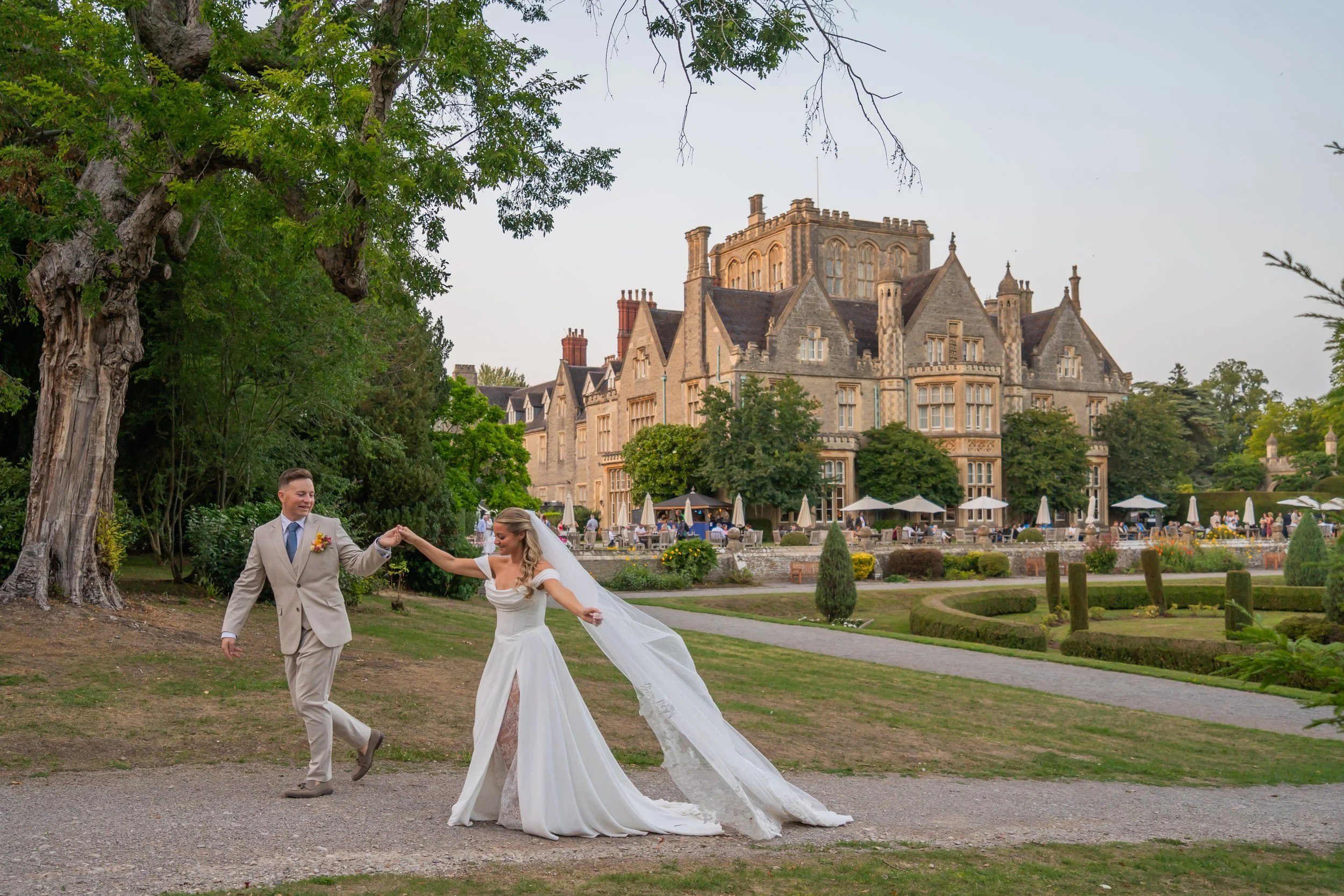 Newlyweds walking hand in hand through the grounds of Tortworth Court.jpg