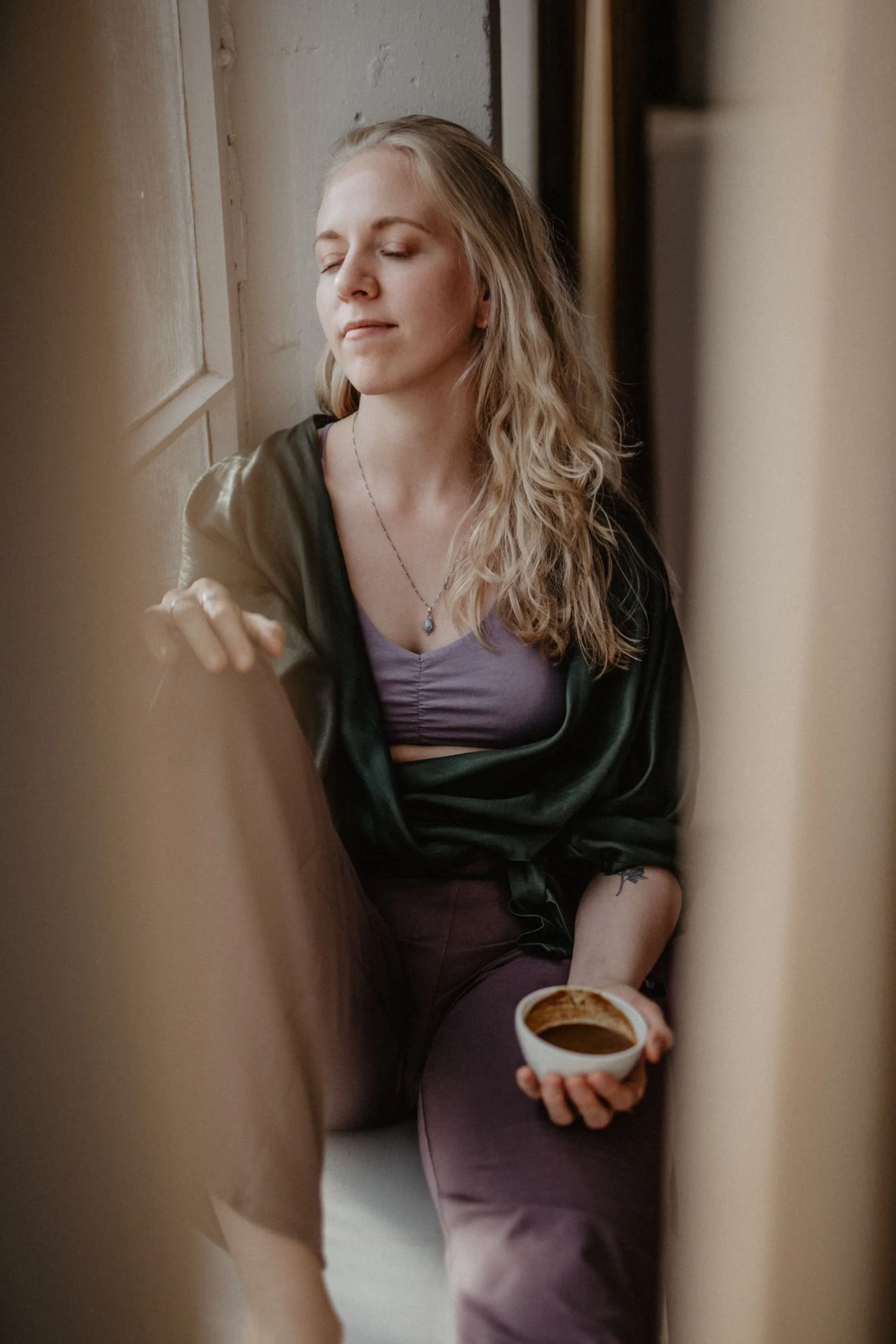 Leona Roes mit einer Tasse zeremoniellem Kakao in der Hand, die Augen entspannt geschlossen.