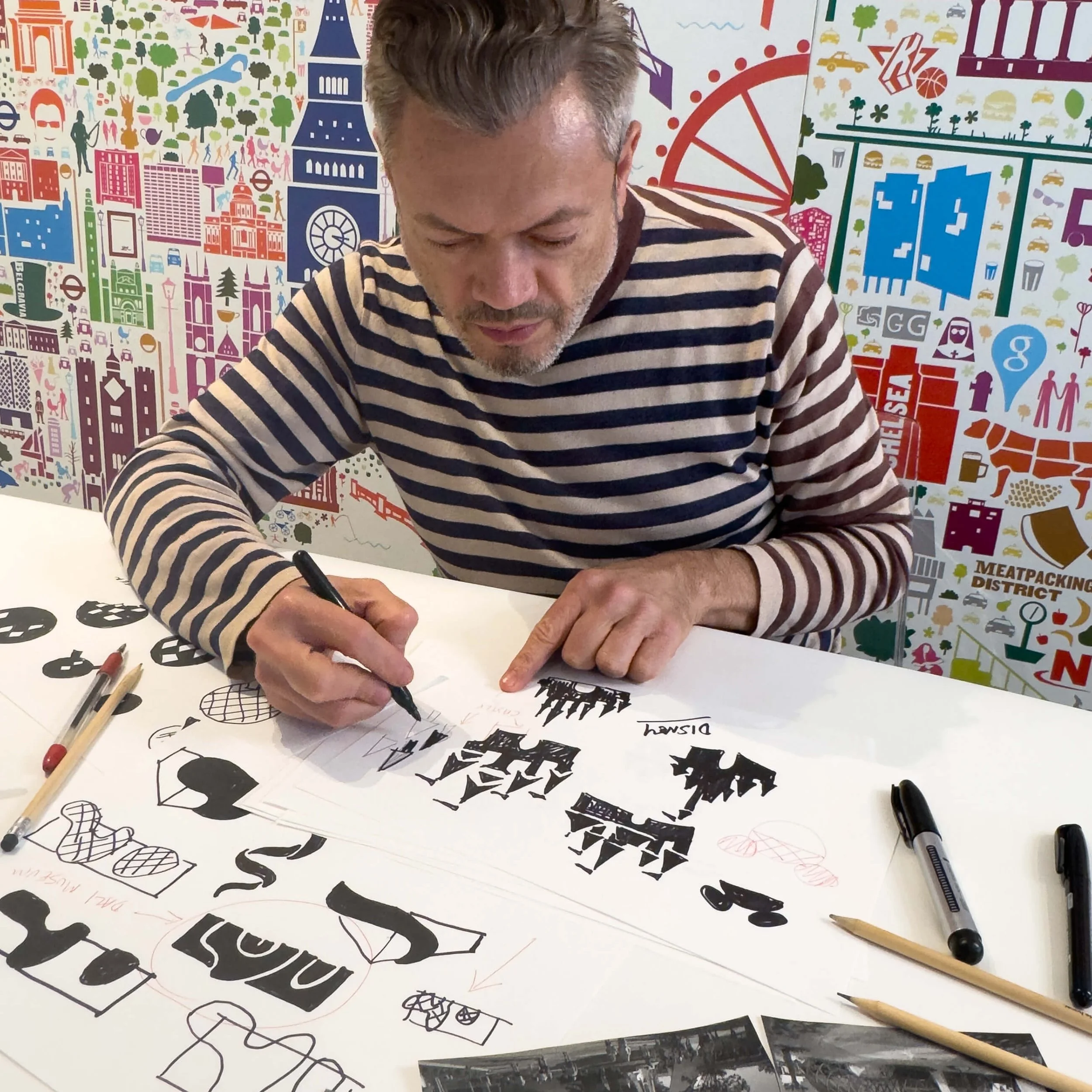 Rafael Esquer working in the studio on the Iconic Florida Poster, refining hand-drawn icons surrounded by sketches, references, and other illustrated poster work.