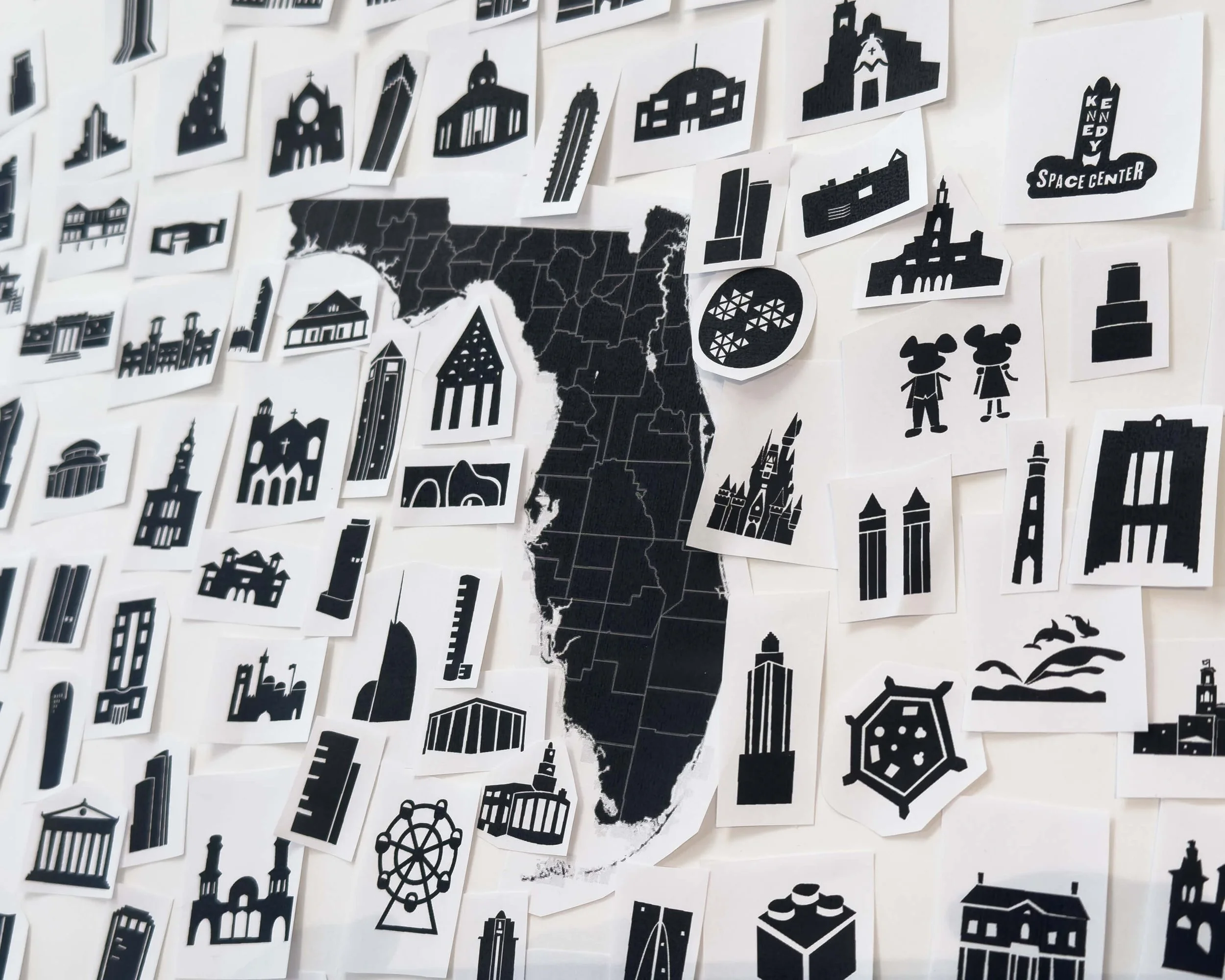 Behind the scenes at Alfalfa Studio during the creation of the Iconic Florida Poster, with hand-cut icons arranged around the Florida map as the composition begins to take shape.