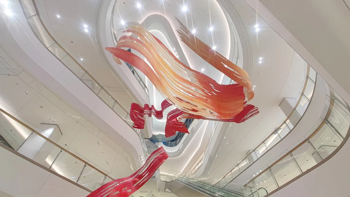 Suspended sculpture of a painted brushstroke hanging in a 7 storey atrium