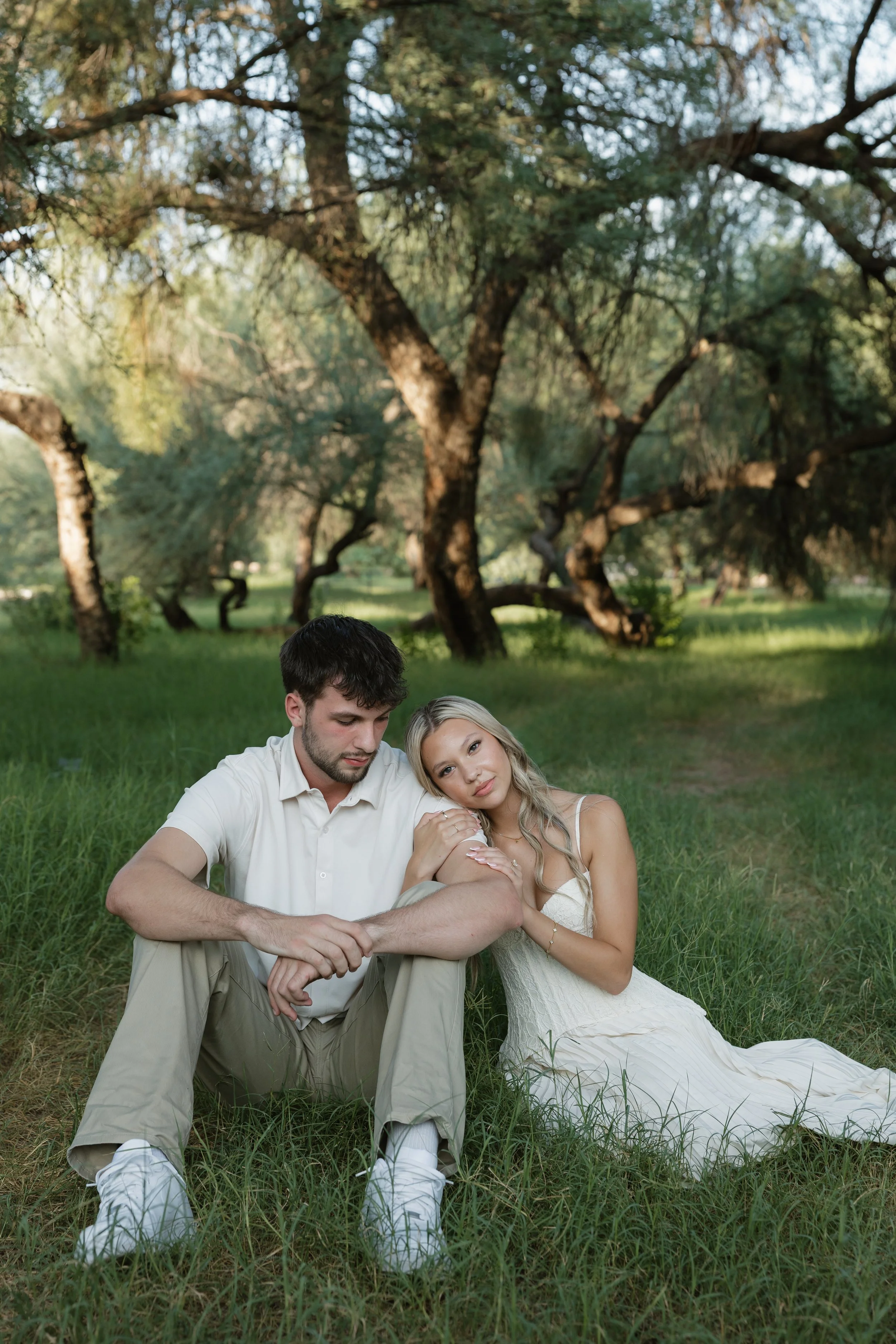 couple sitting in a field posing for their engagement photos