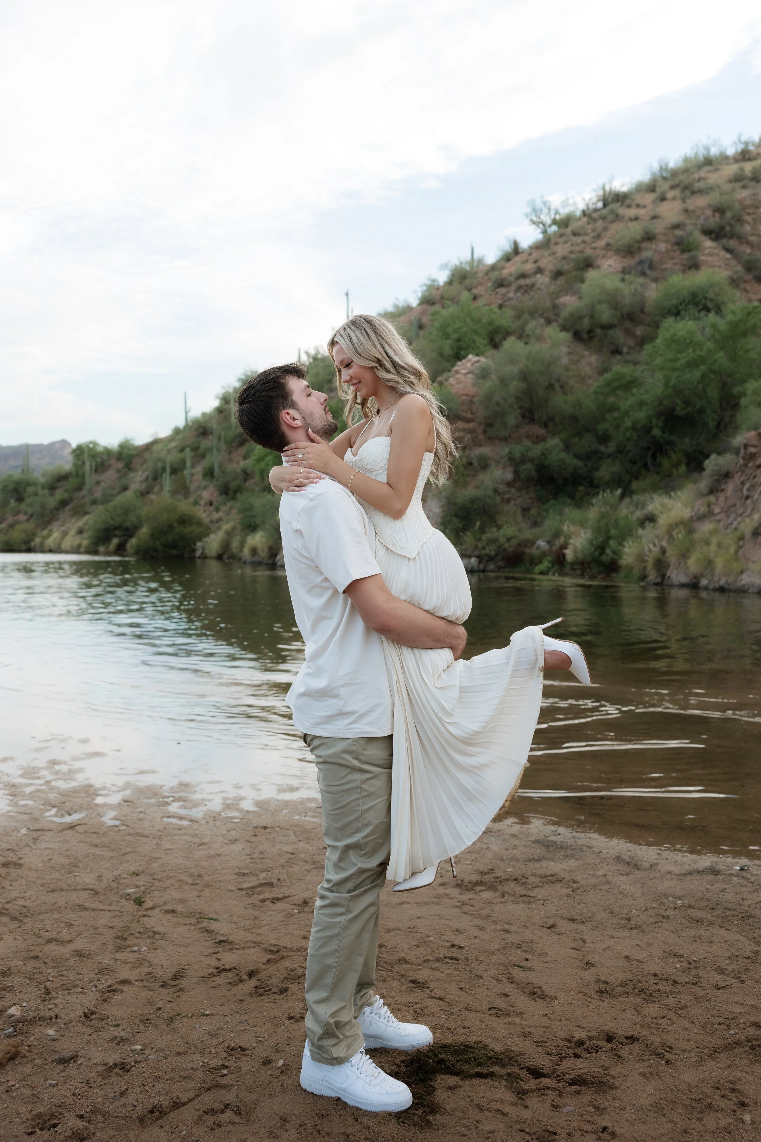 playful engagement photos with the groom lifting up the bride by the lake in arizona