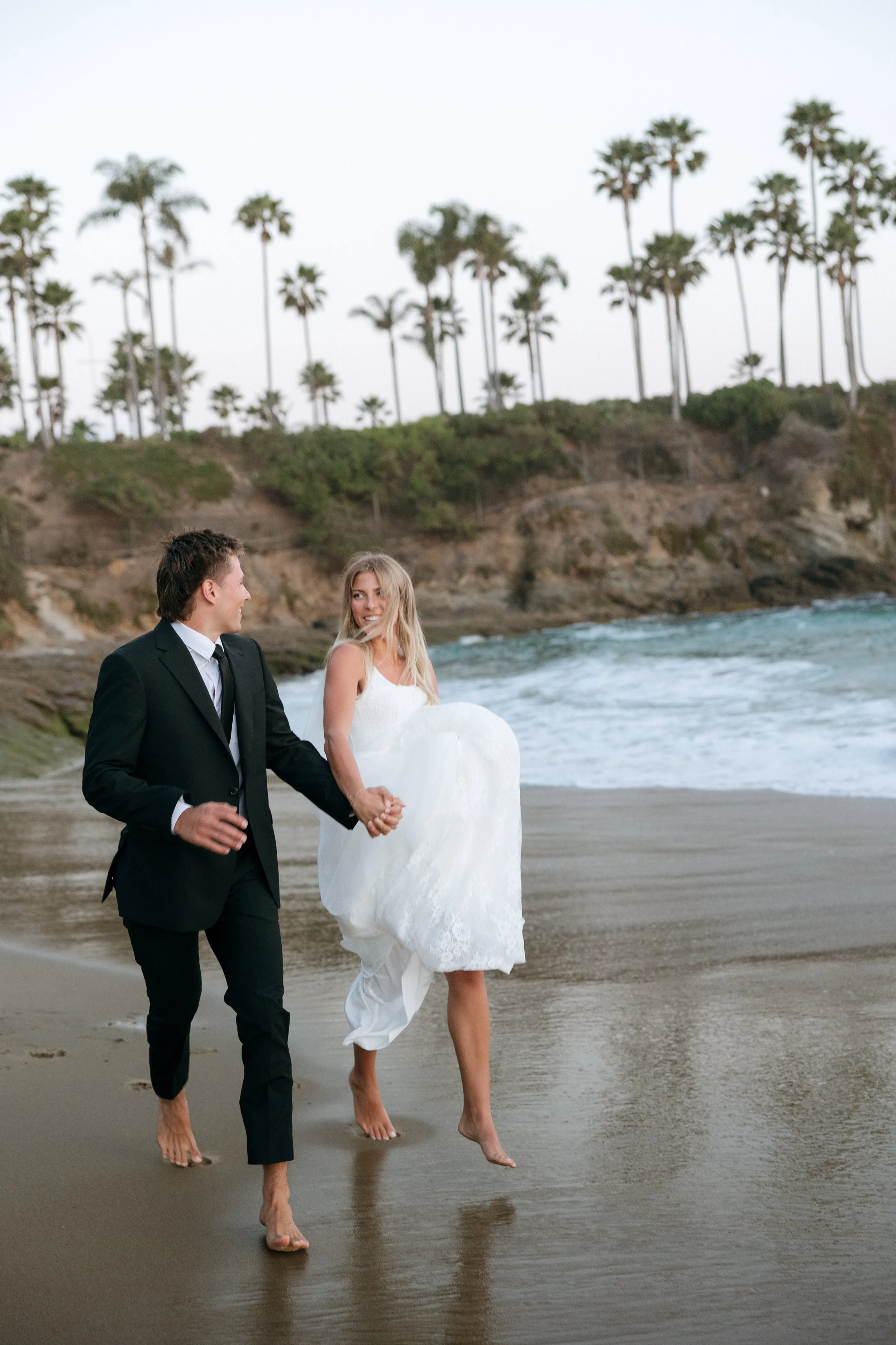 bride and groom running on beach