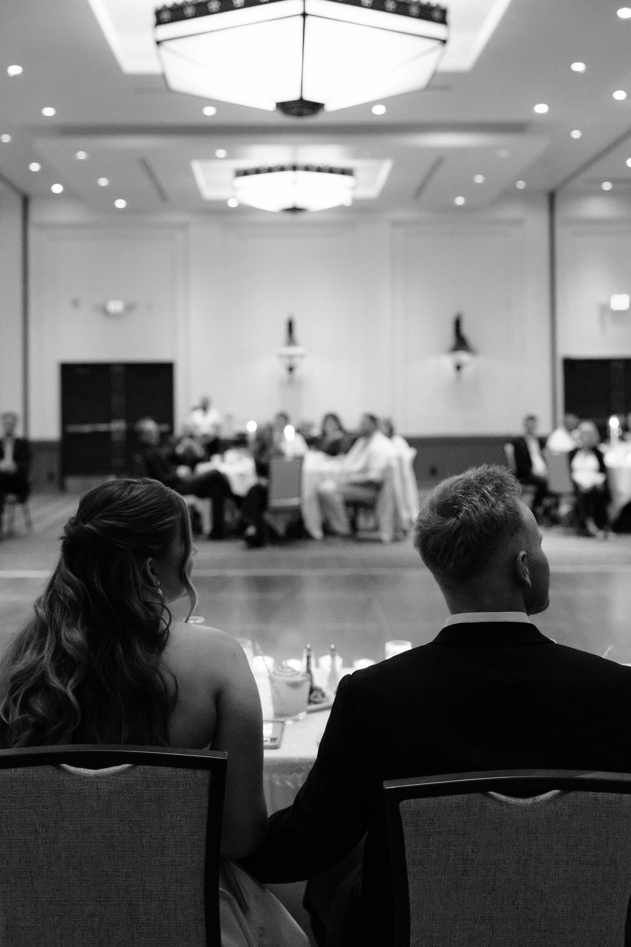 Newlyweds watching their guests from sweetheart table at The Scott Resort & Spa wedding reception