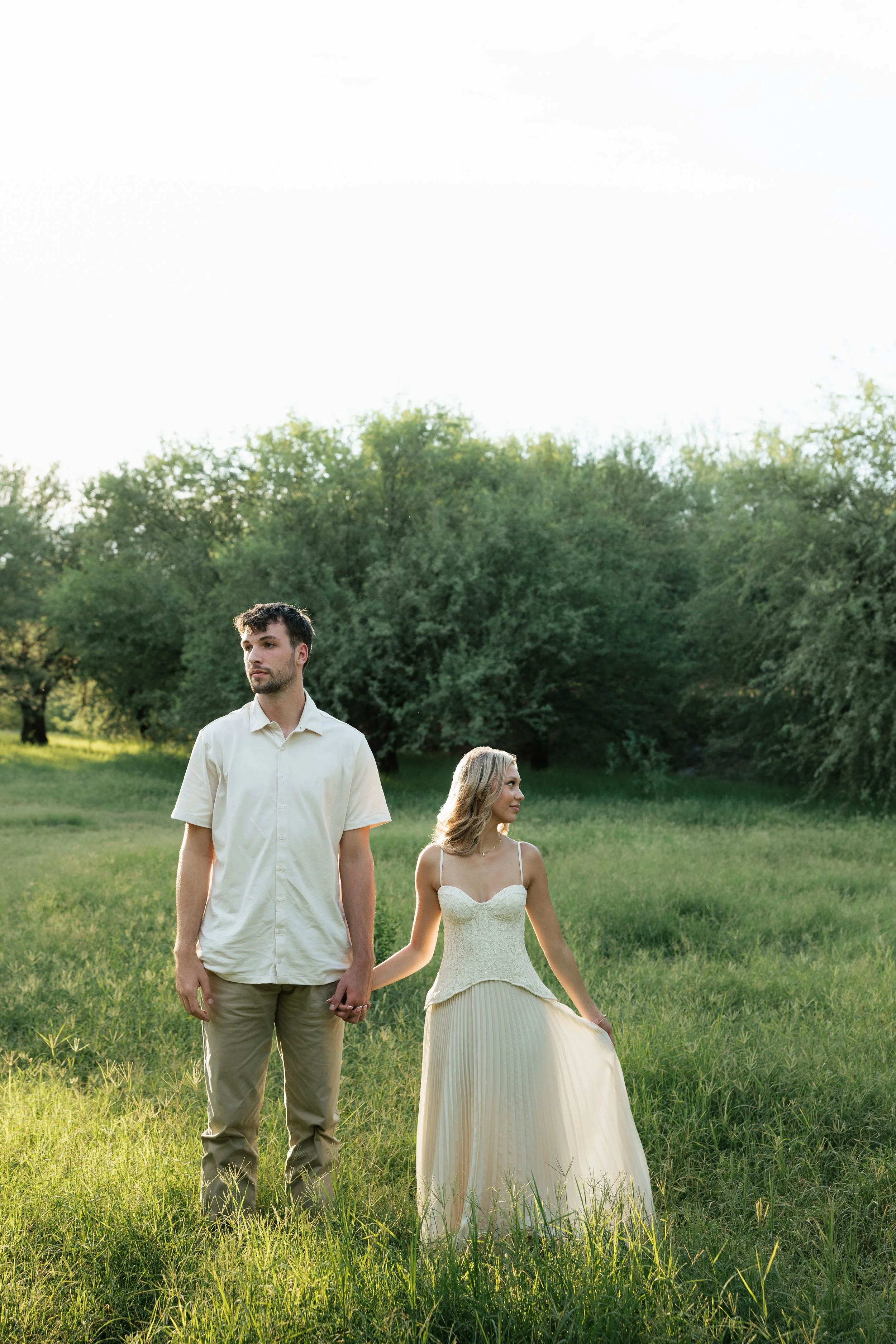 a couple in a green field posing for engagement photos at butcher jones arizona