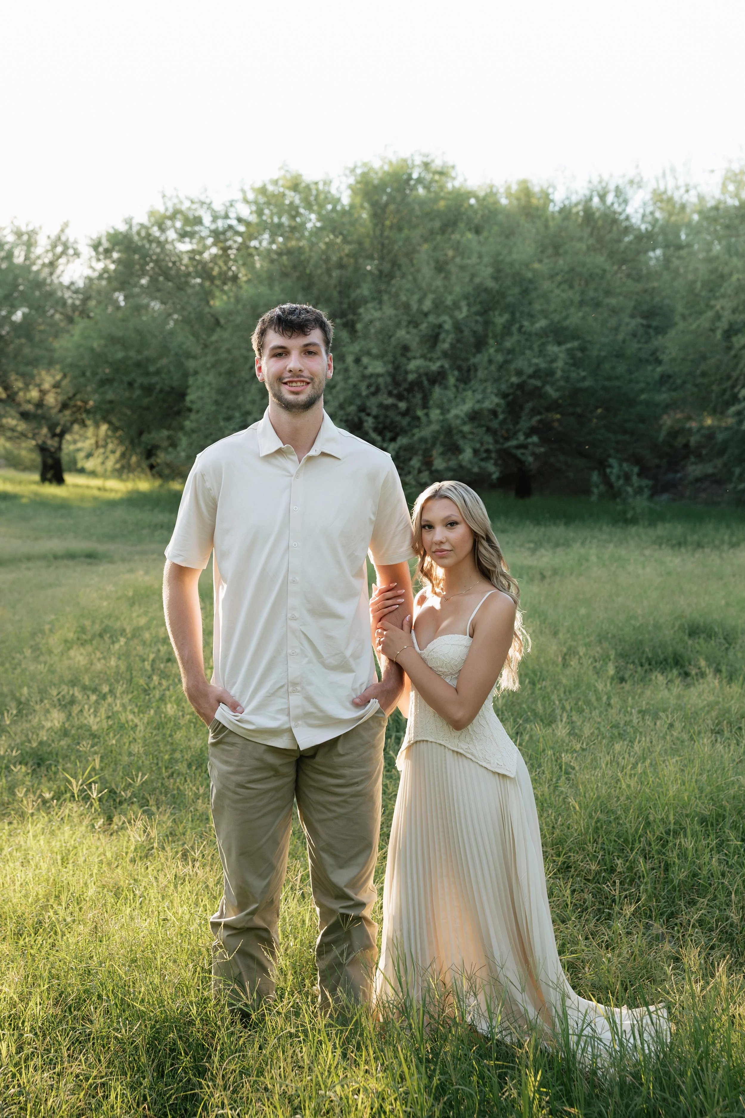 engaged couple standing in a field at golden hour posing for engagement photos in arizona