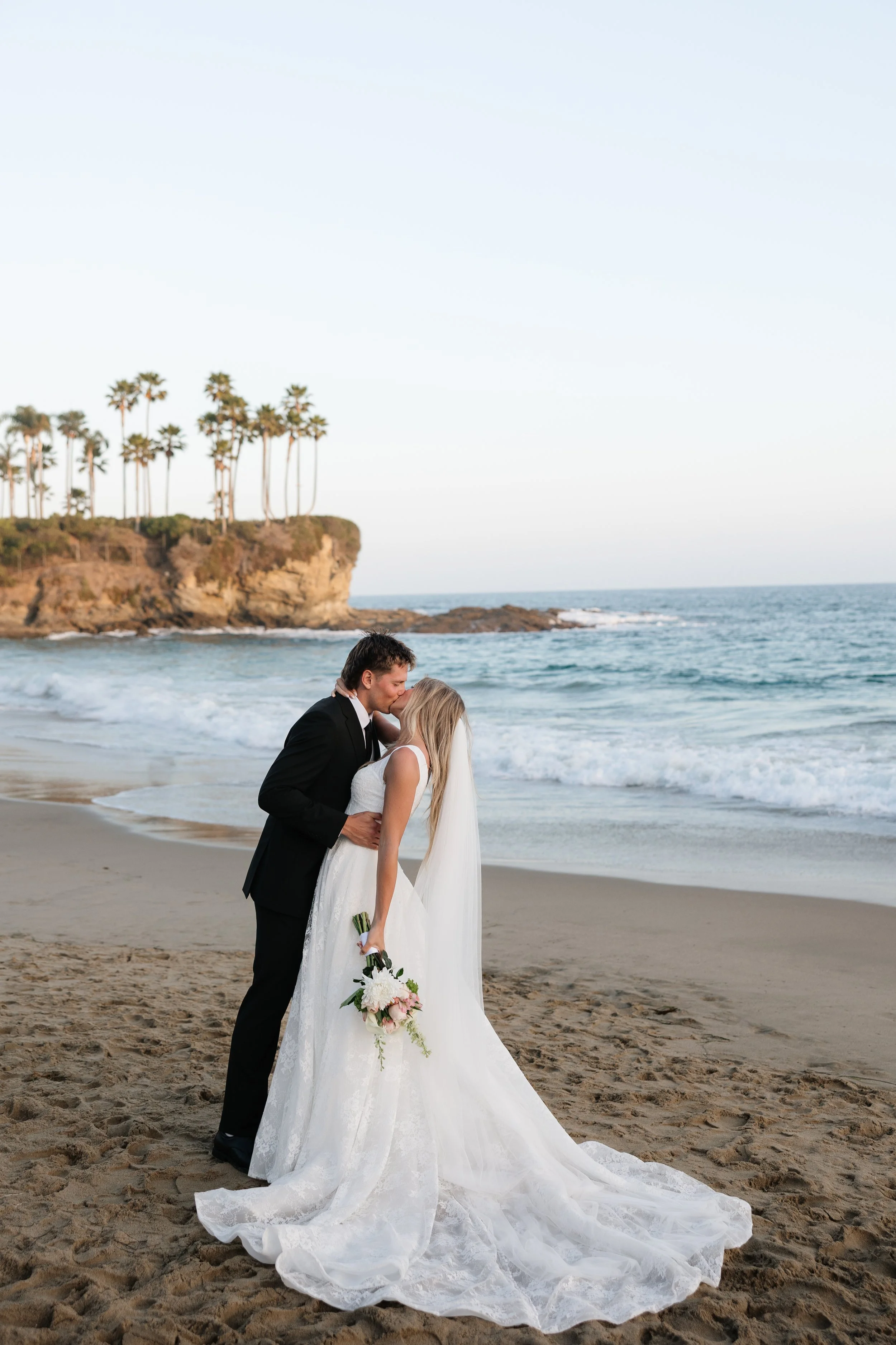 bride and groom kissing on the beach at golden hour in laguna beach california