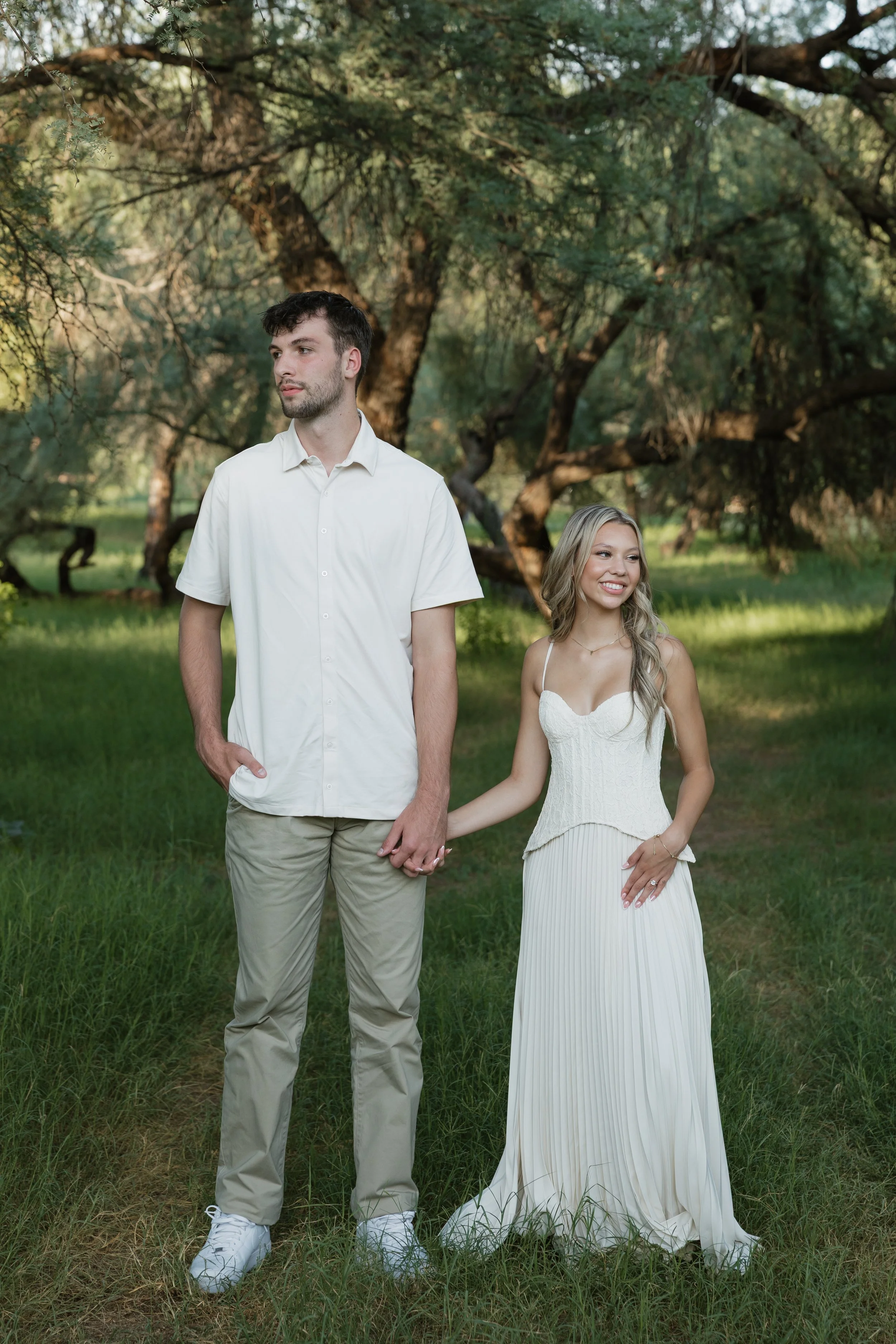 couple posing for engagements photos in arizona in a green field