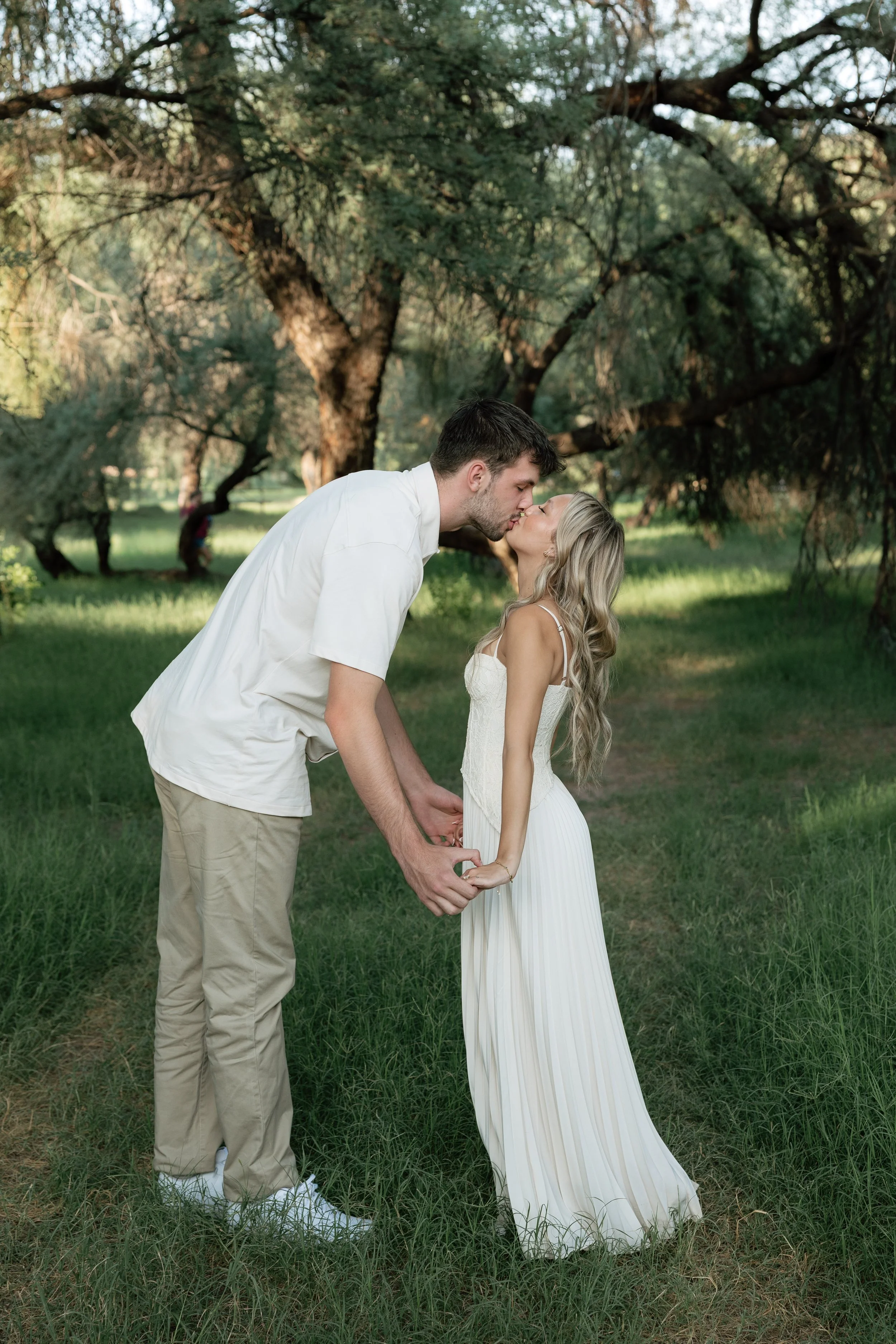 engaged couple kissing in green field during their engagement session