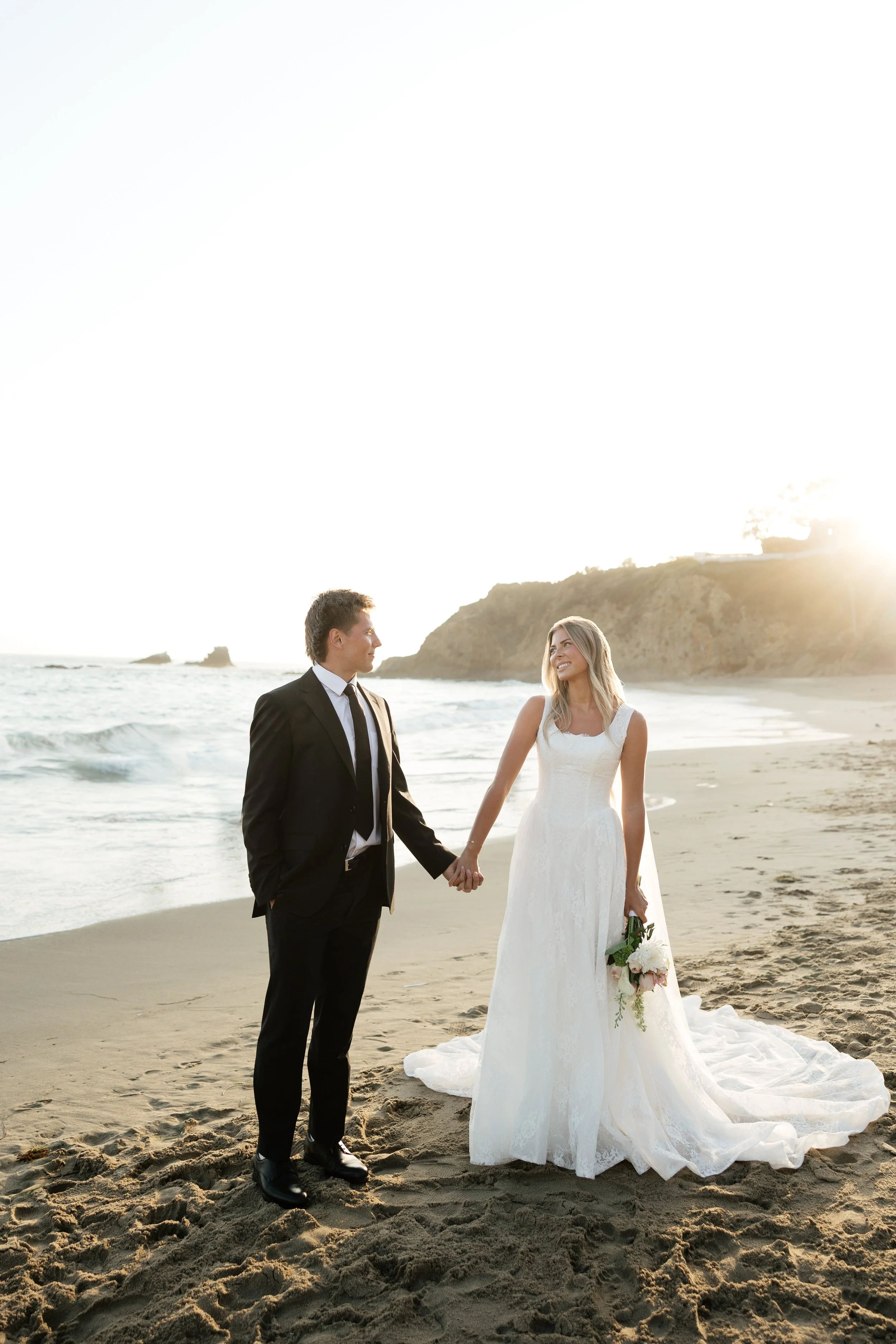 bride and groom smiling at each other during bridal portraits at crescent bay beach in orange county