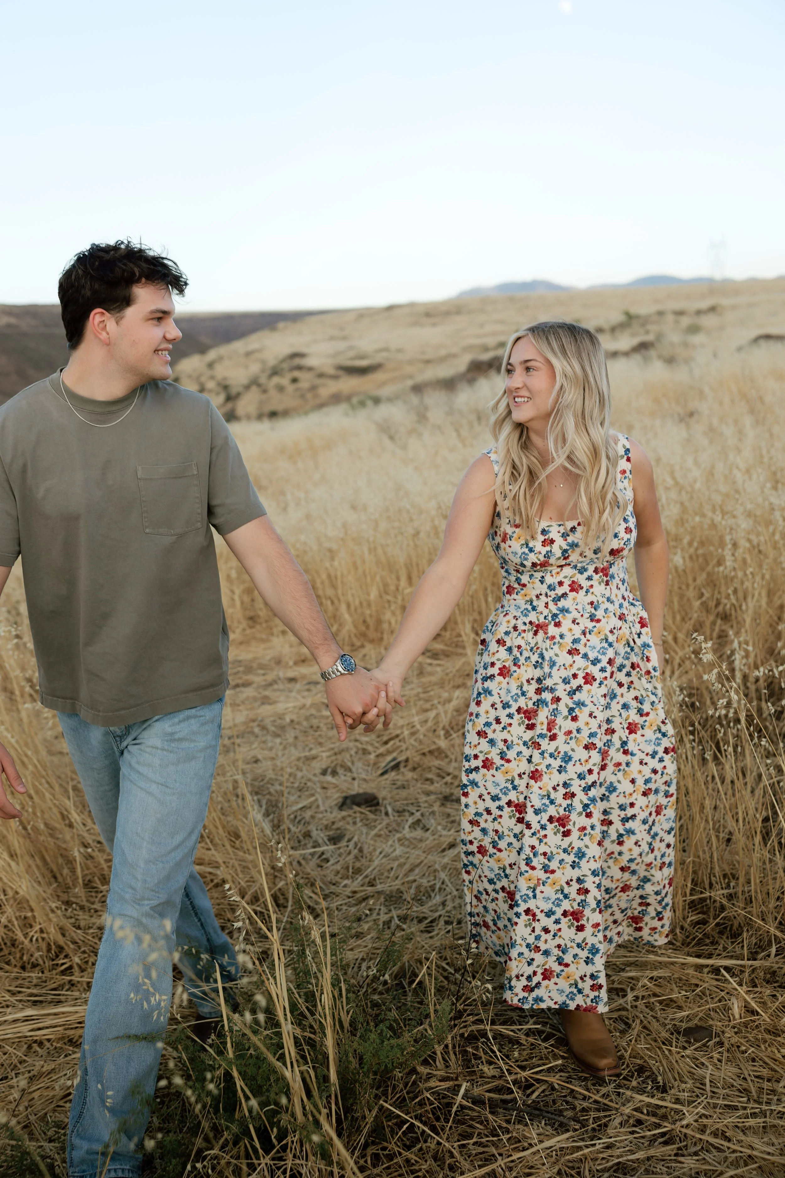 Couple standing together in golden grass during an Arizona engagement session at sunset