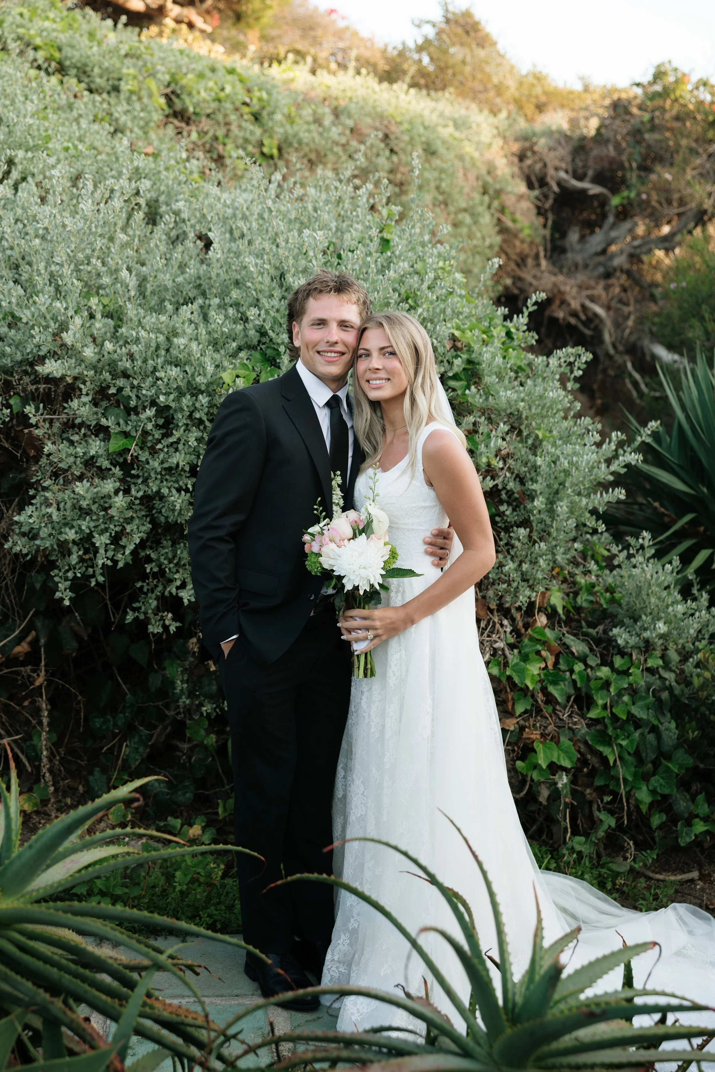 bride and groom looking at the camera smiling after their first look in orange county california