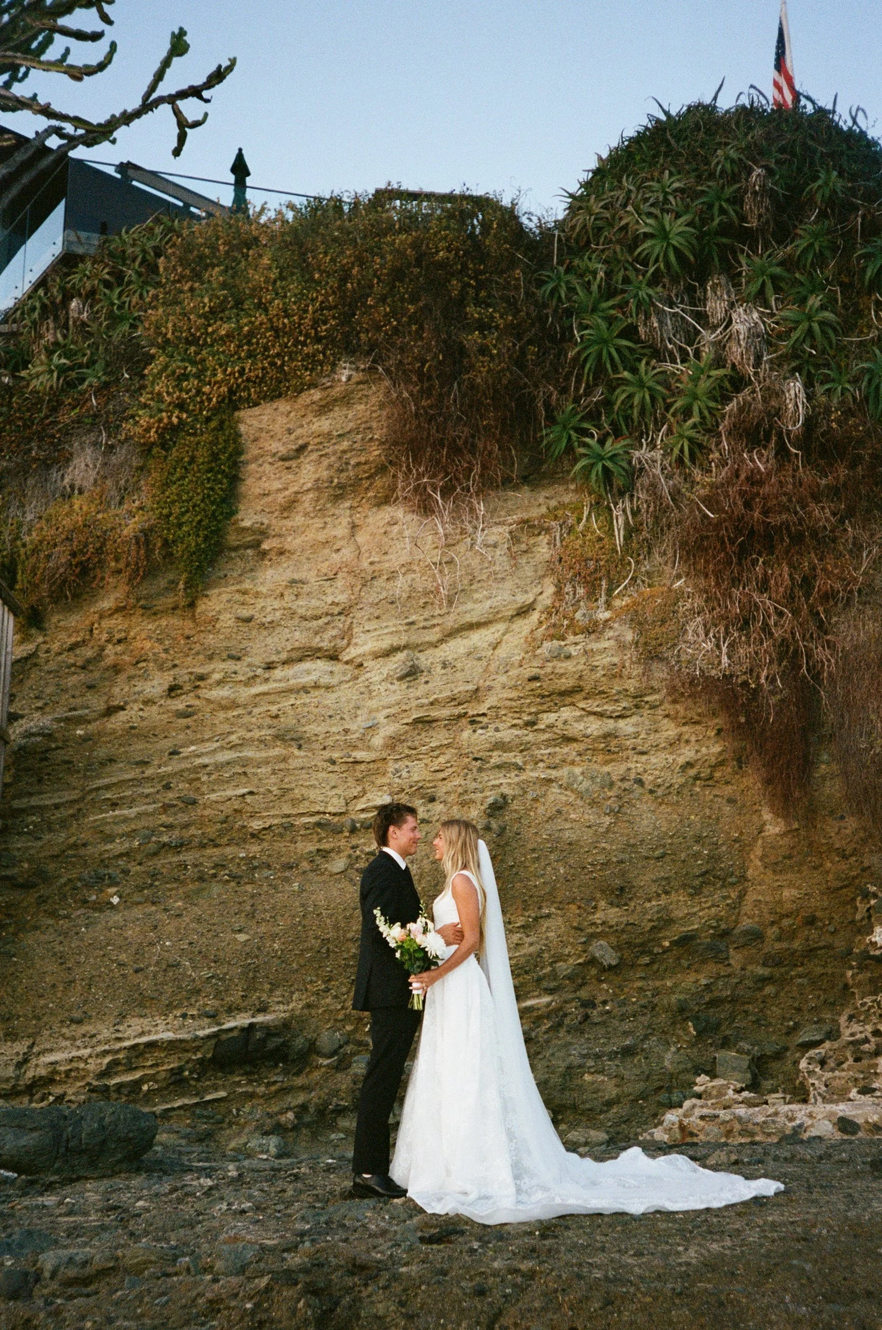 35mm film image of bride and groom posing on the rocky coastline of laguna beach california
