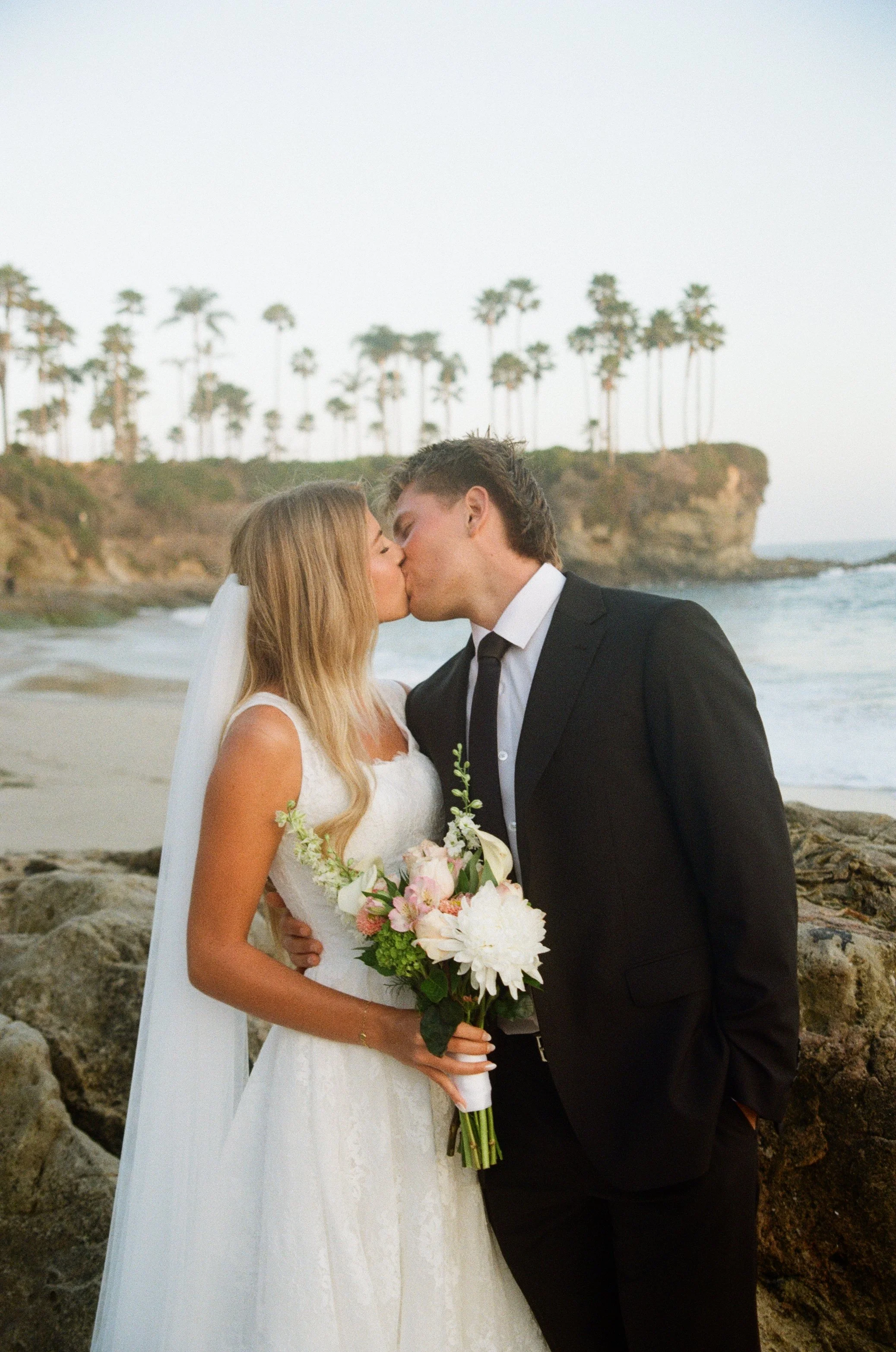 35mm film photo of bride and groom kissing on the beach