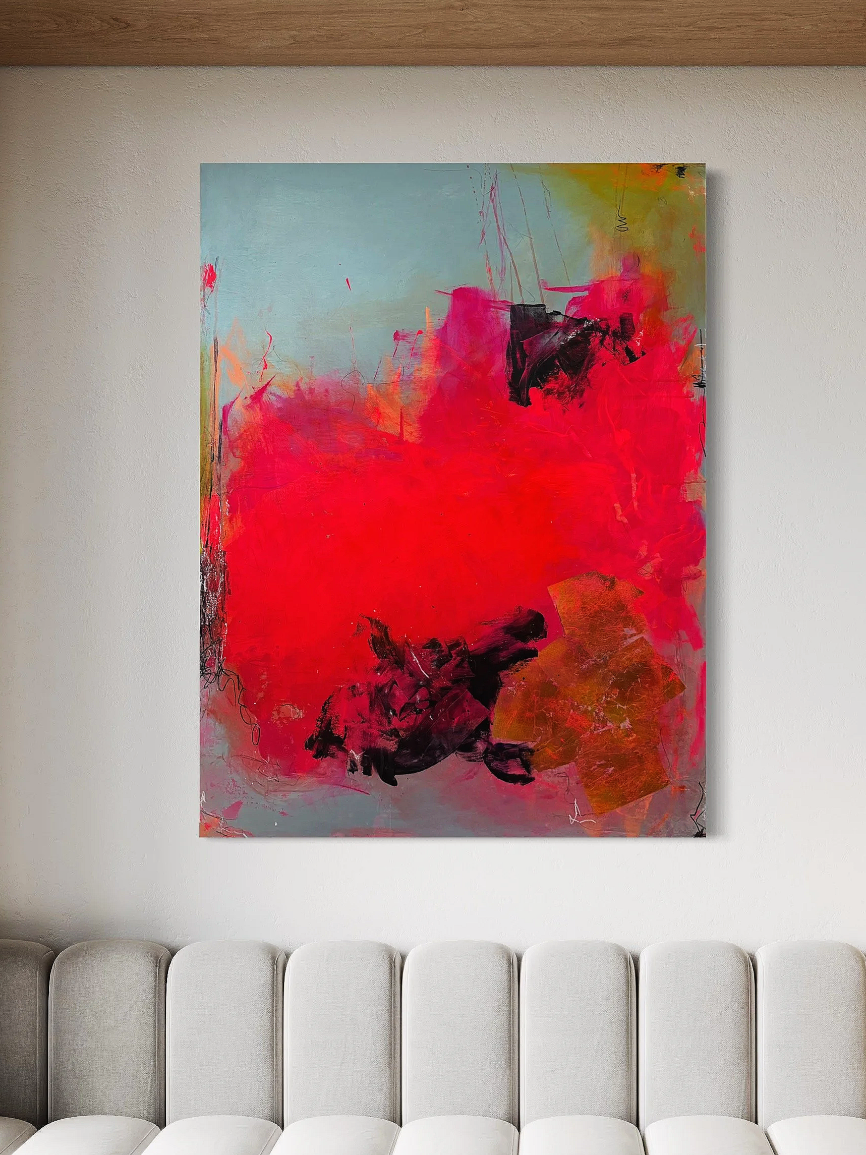 Abstract painting with vibrant red, pink, black, blue, green, and orange colors hung on a white wall above a row of beige upholstered chairs.