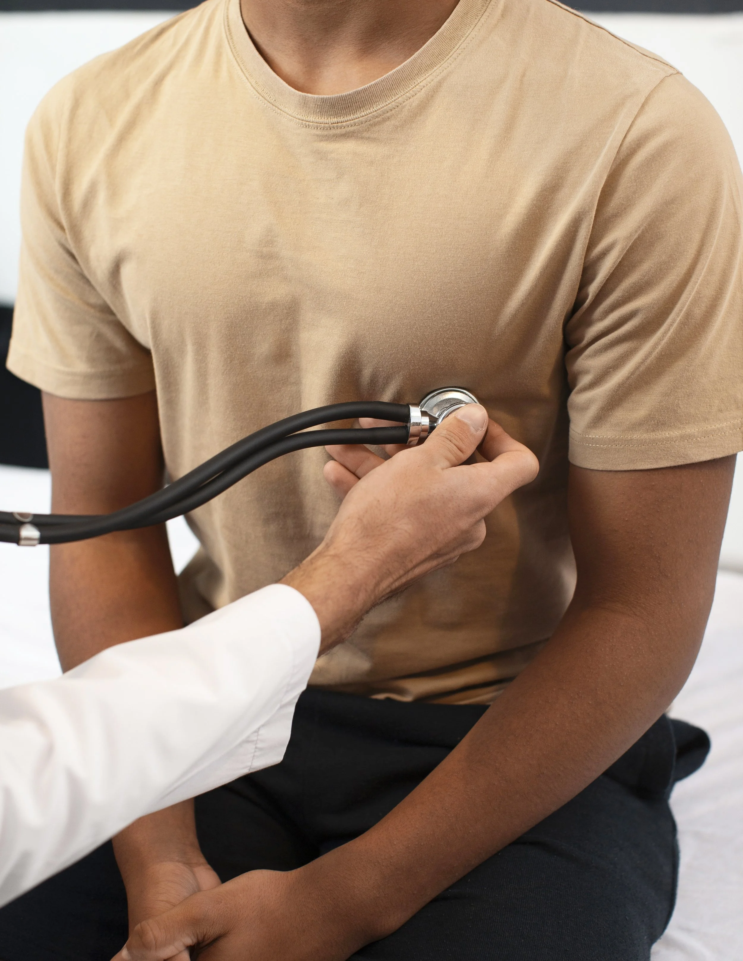 Doctor using a stethoscope on a patient's chest during a medical examination.