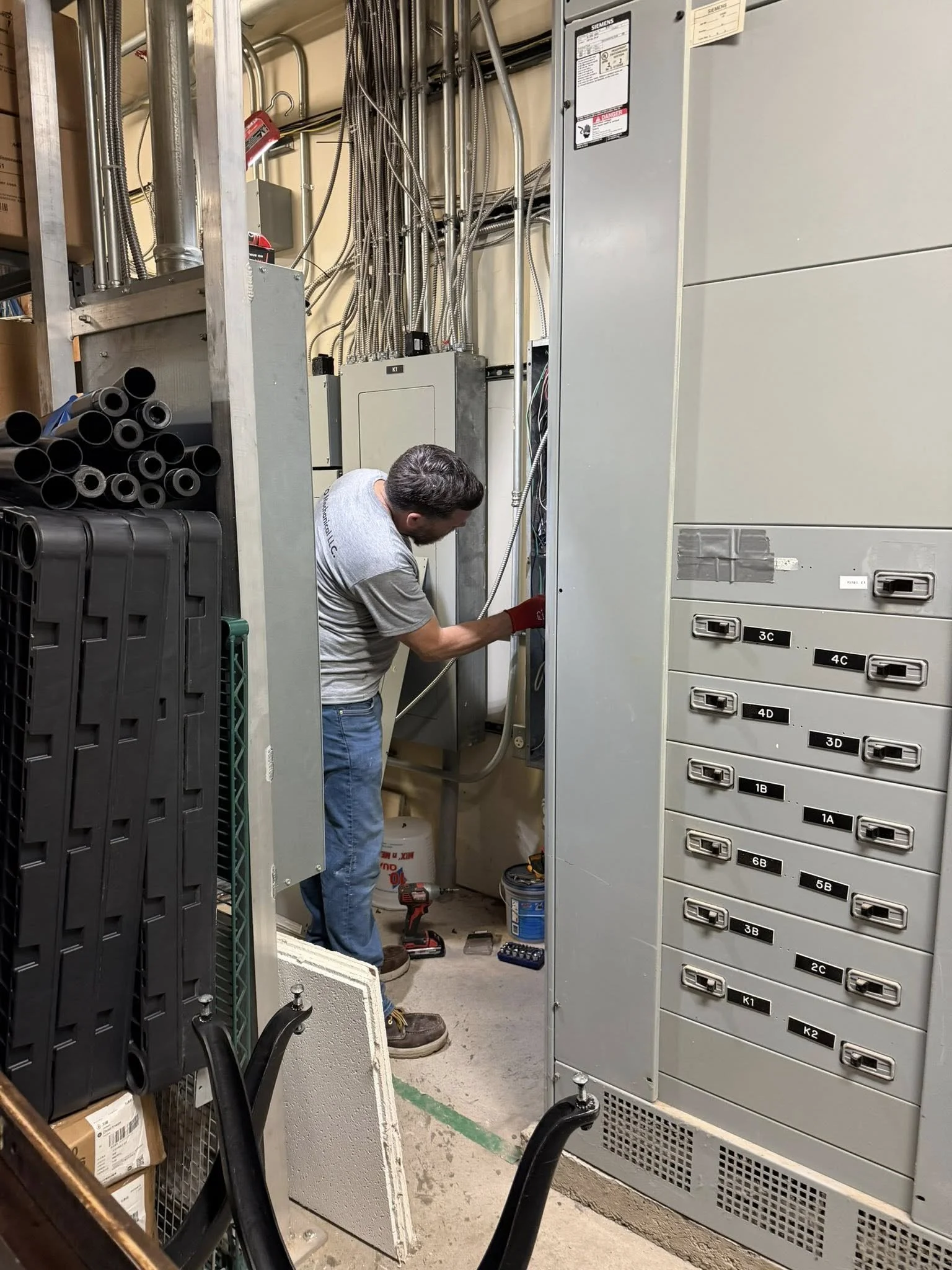 Commercial mini split installation with new electrical wiring, technician turning on breaker panel to test system operation.