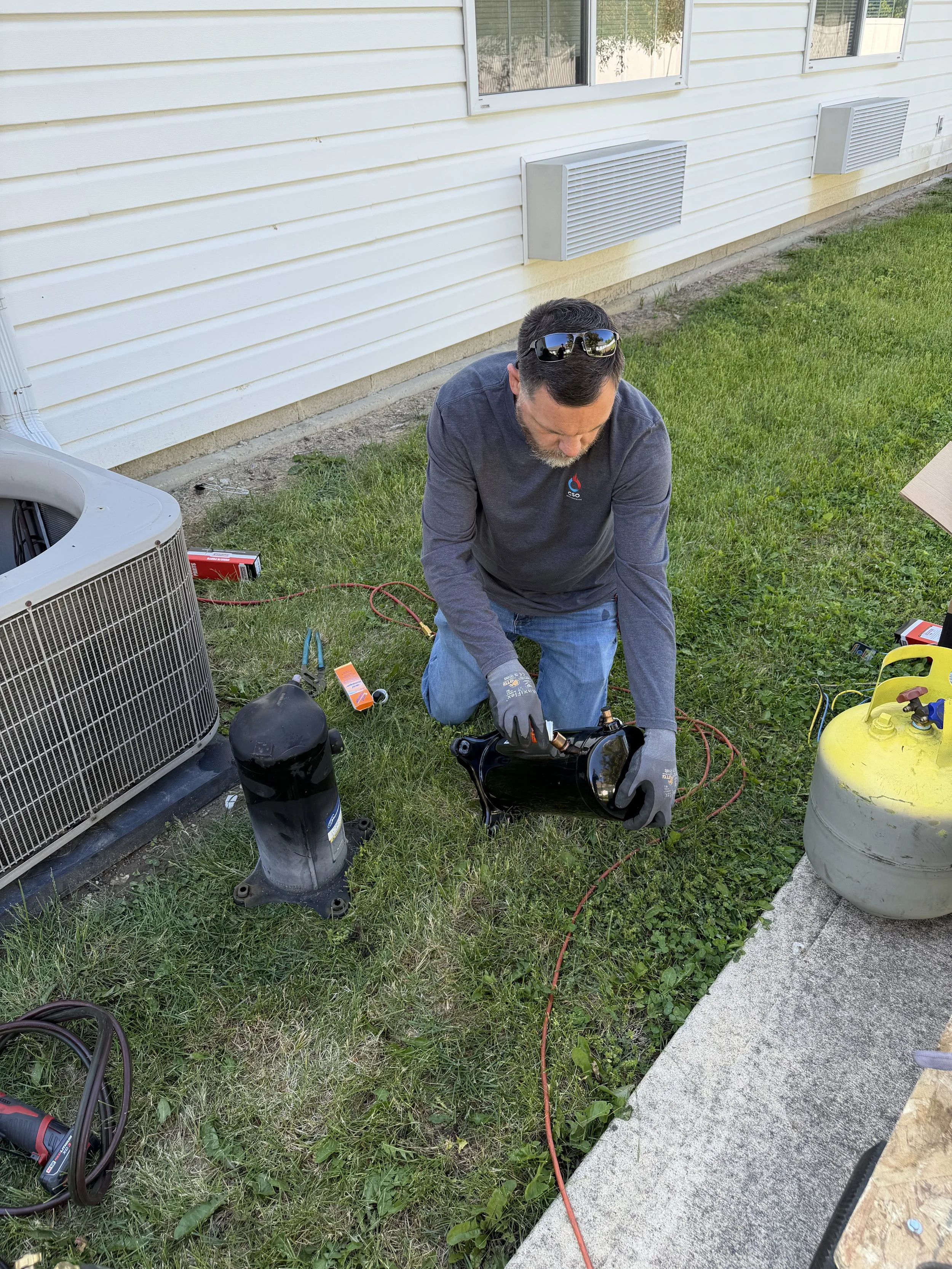 HVAC technician replacing compressor for outdoor air conditioning unit.