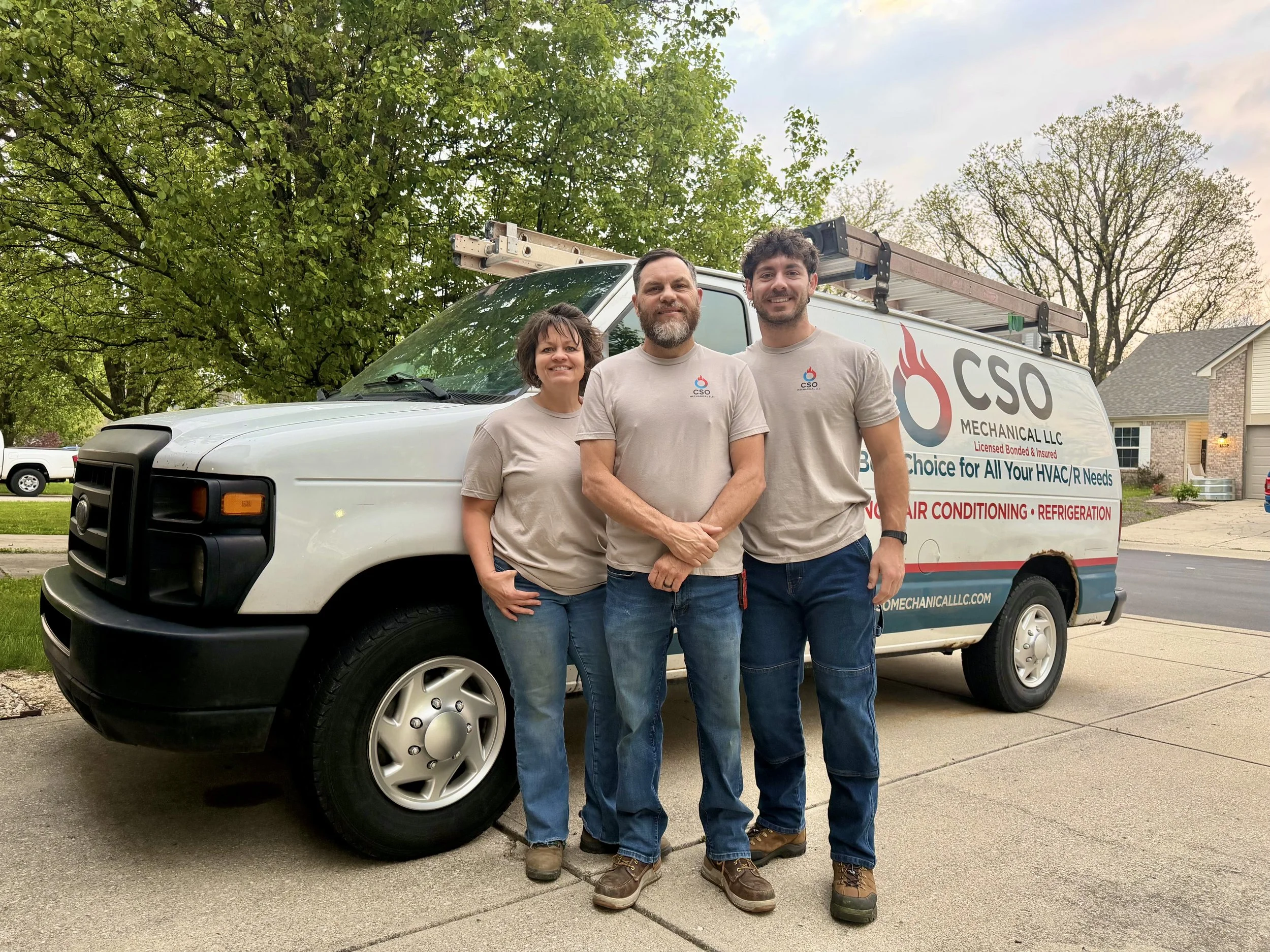A amily standing in front of their HVAC business van.