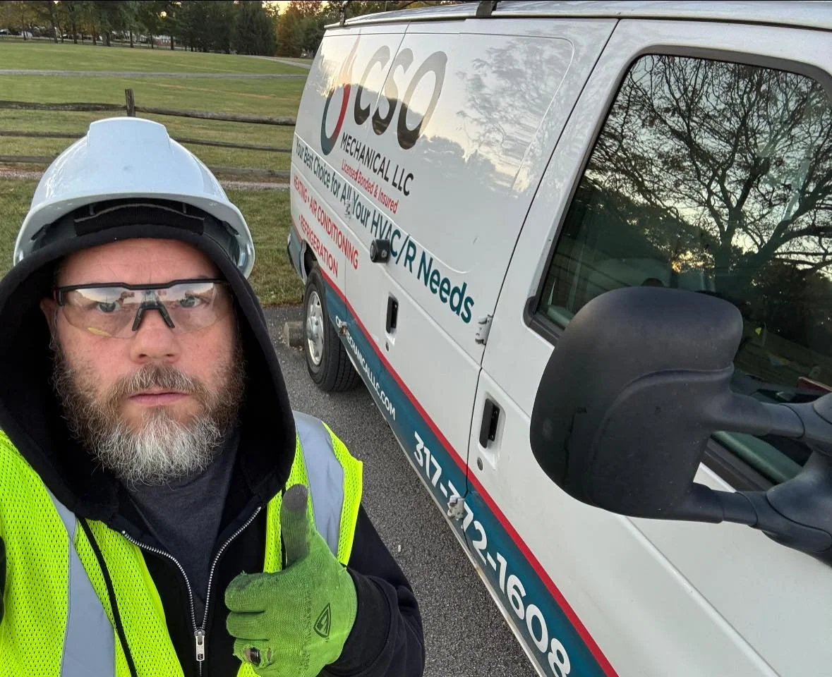 A man wearing a yellow safety vest, helmet, and safety glasses giving a thumbs up at a work site, standing next to a white service van with company branding for CSC Mechanical LLC.