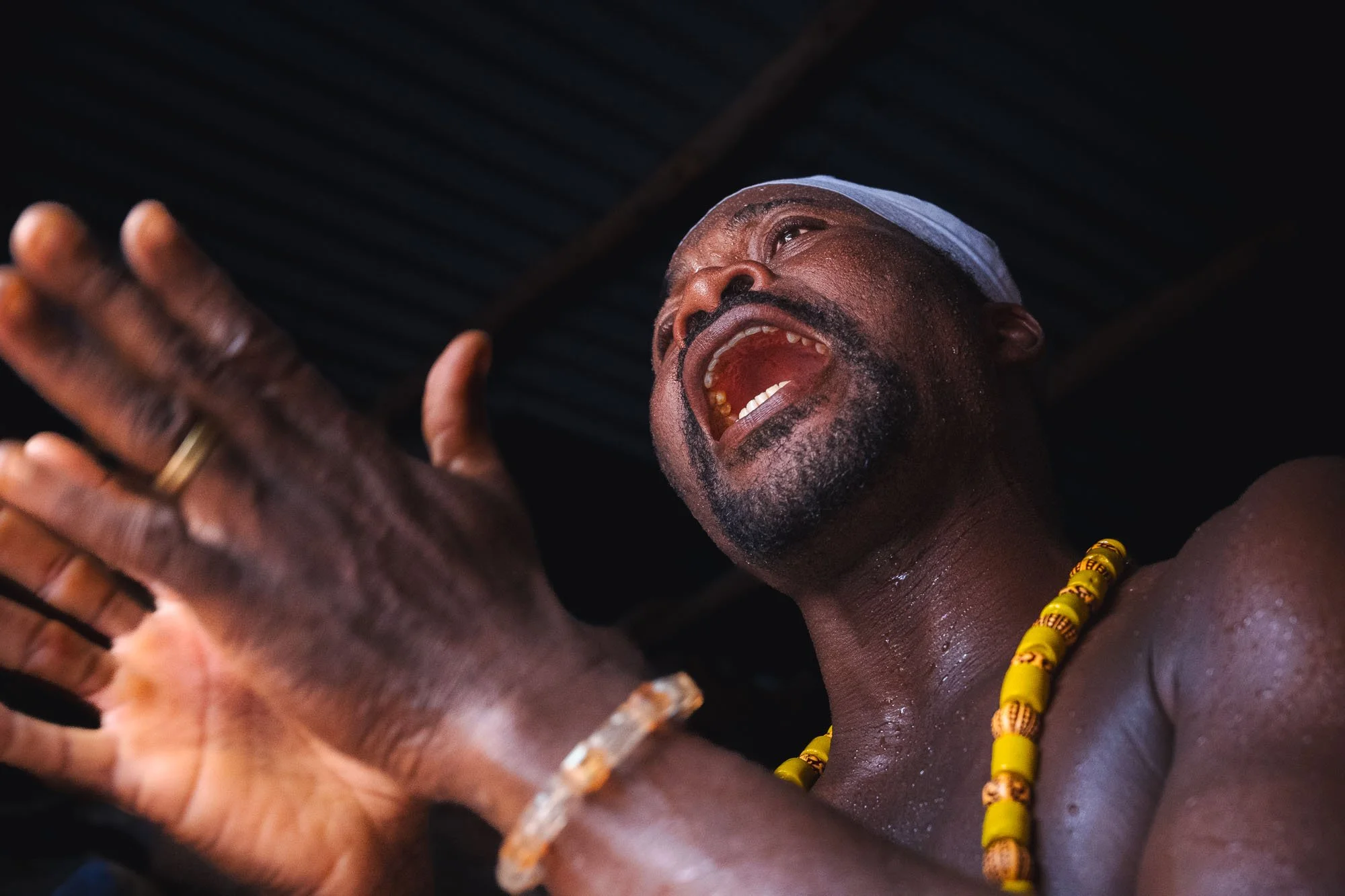 Close-up of a sweating Vodun Priest singing and clapping in spiritual devotion during a Mami Wata ceremony in Benin