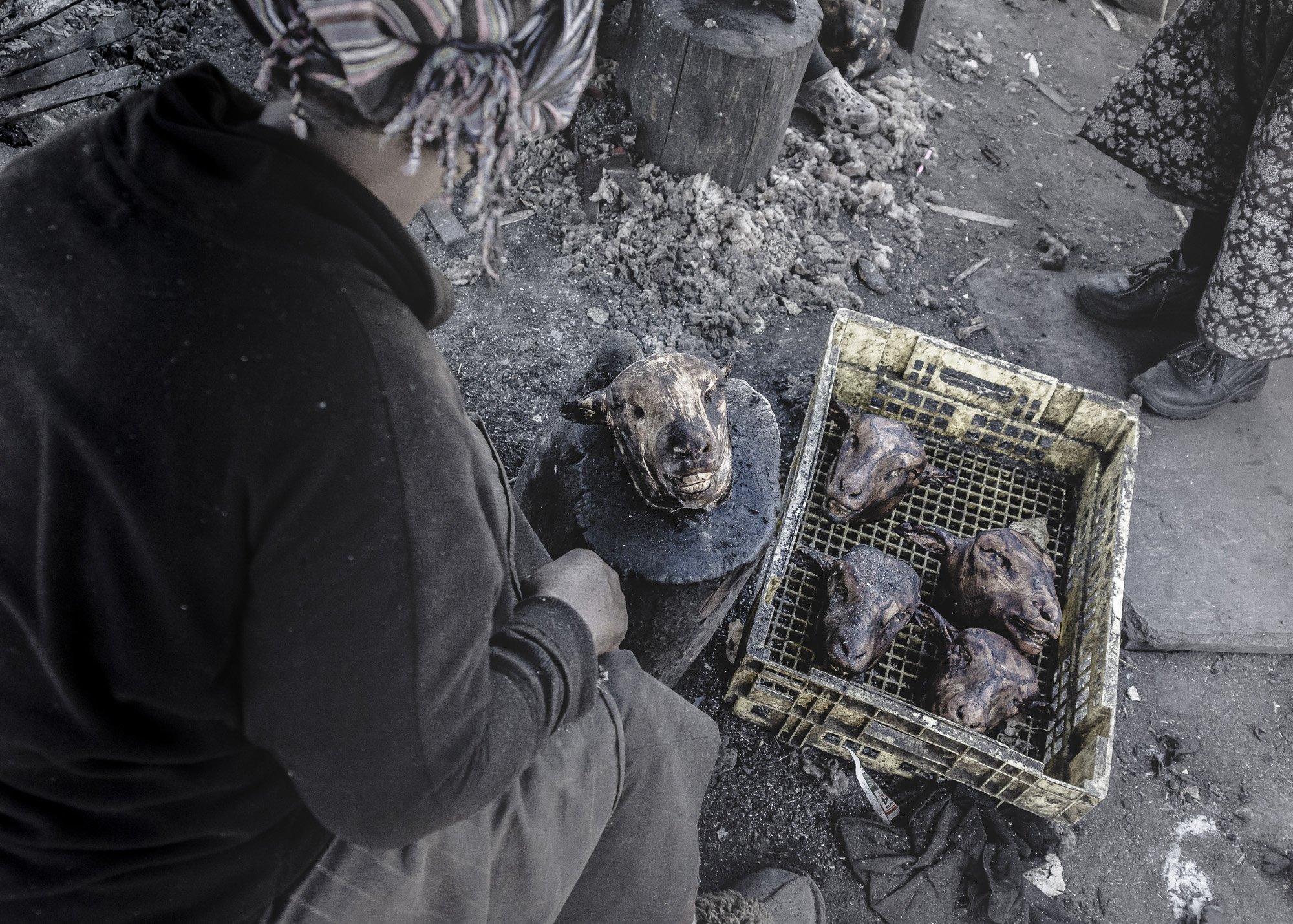 A gritty, documentary-style shot of a makeshift 'smiley' butchery in South Africa. The stark, unusual subject matter serves as a powerful visual anchor, rewarding the viewer for using top-down processing to interpret the cultural and narrative contex