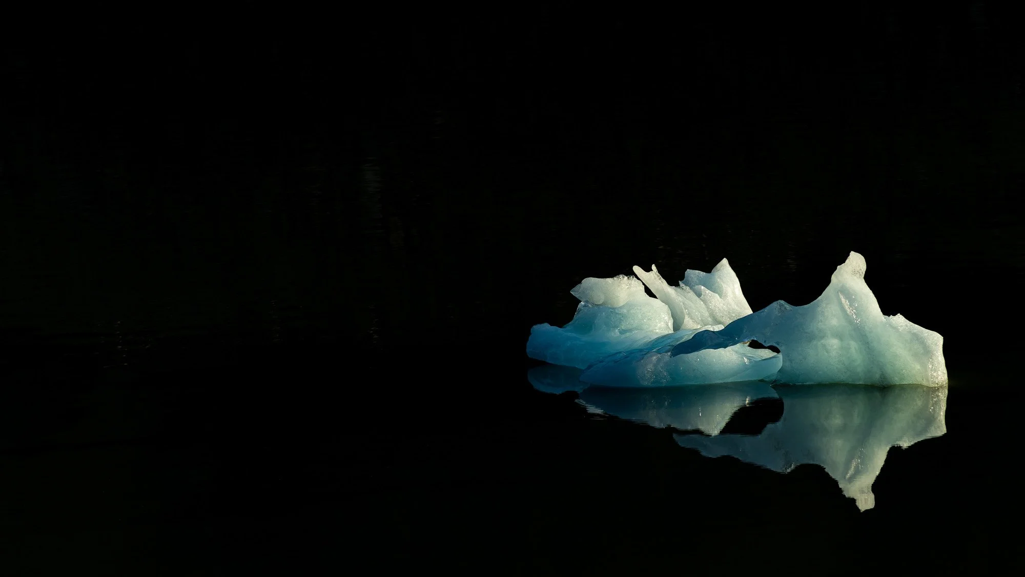 A glowing blue iceberg fragment in El Chaltén, Argentina, surrounded by deep black negative space. This composition utilizes 'The Art of Subtraction' to force the viewer to focus entirely on texture and form.