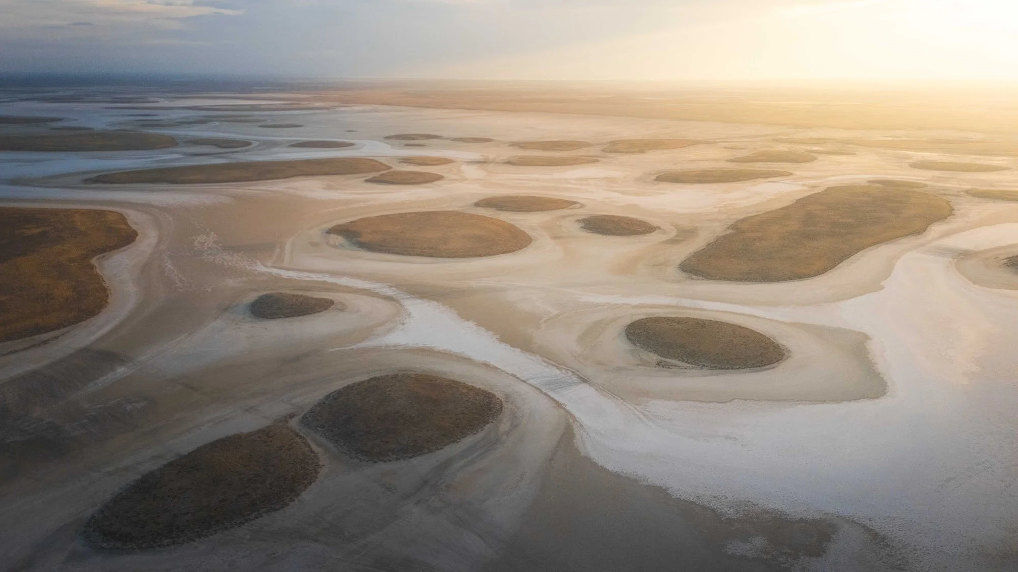 A vast, abstract aerial photograph of circular patterns in the salt evaporation pools of Lake Tuz (Tuz Golu), Türkiye, demonstrating how scale creates visual ambiguity.