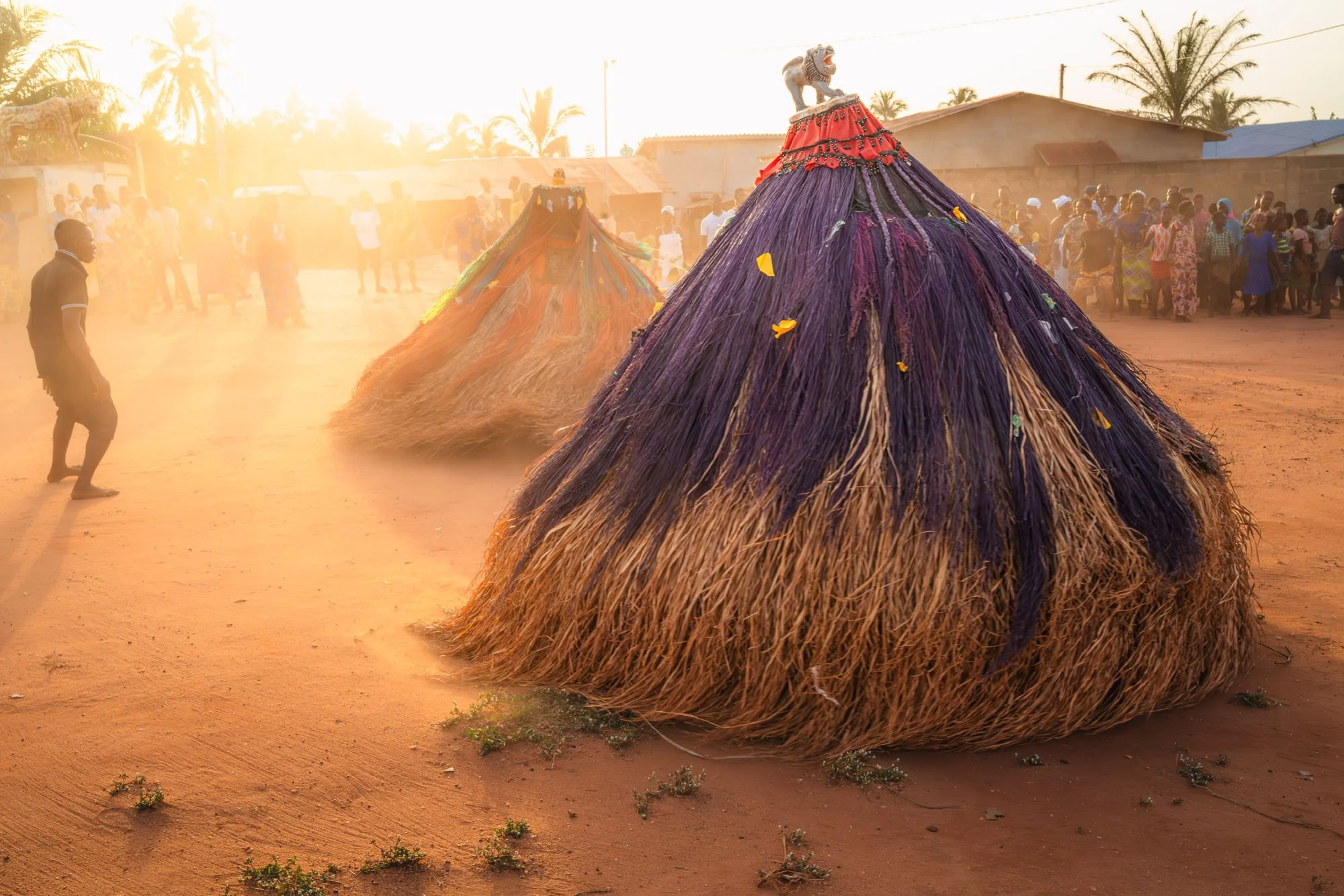 A Zangbeto guardian spins rapidly, kicking up a massive cloud of dust in the golden hour light of Benin. This frame illustrates the 'Signal in the Noise,' where chaos is used to create a cinematic, high-retention atmosphere.