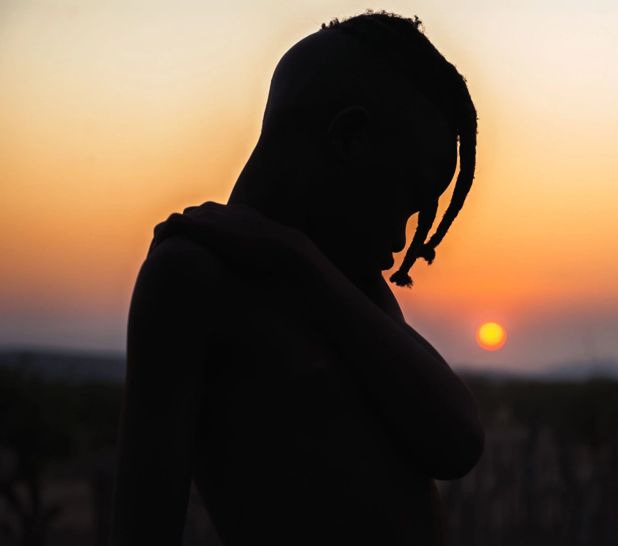 A silhouette of a Himba child in Namibia against a vibrant orange sunset, illustrating how to strip away romanticism to find a pure biological visual signal.