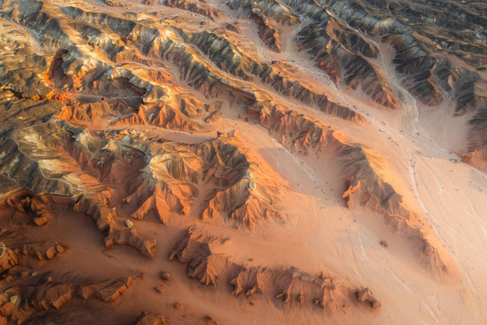An aerial view of heavily eroded, terracotta-colored desert badlands. By ignoring local landmarks to find this weathered landscape, the image captures an unexpected and authentic geological signal.