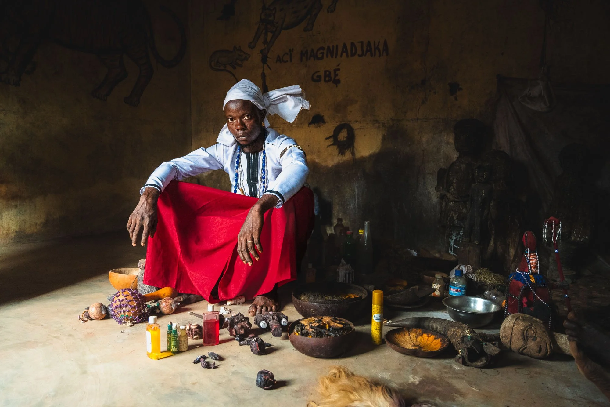 An ethnographic photograph of a Voodoo priest sitting in his shrine in Benin, surrounded by ceremonial objects, highlighting how to read an environment as a psychological signal.