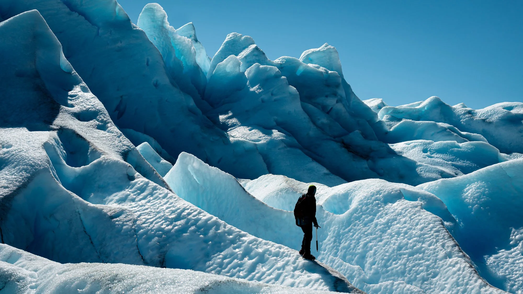 A man standing on the blue ice of the Perito Moreno Glacier in Patagonia, with his back to the camera. This image demonstrates how adventure feels, prioritizing emotional impact over technical perfection.