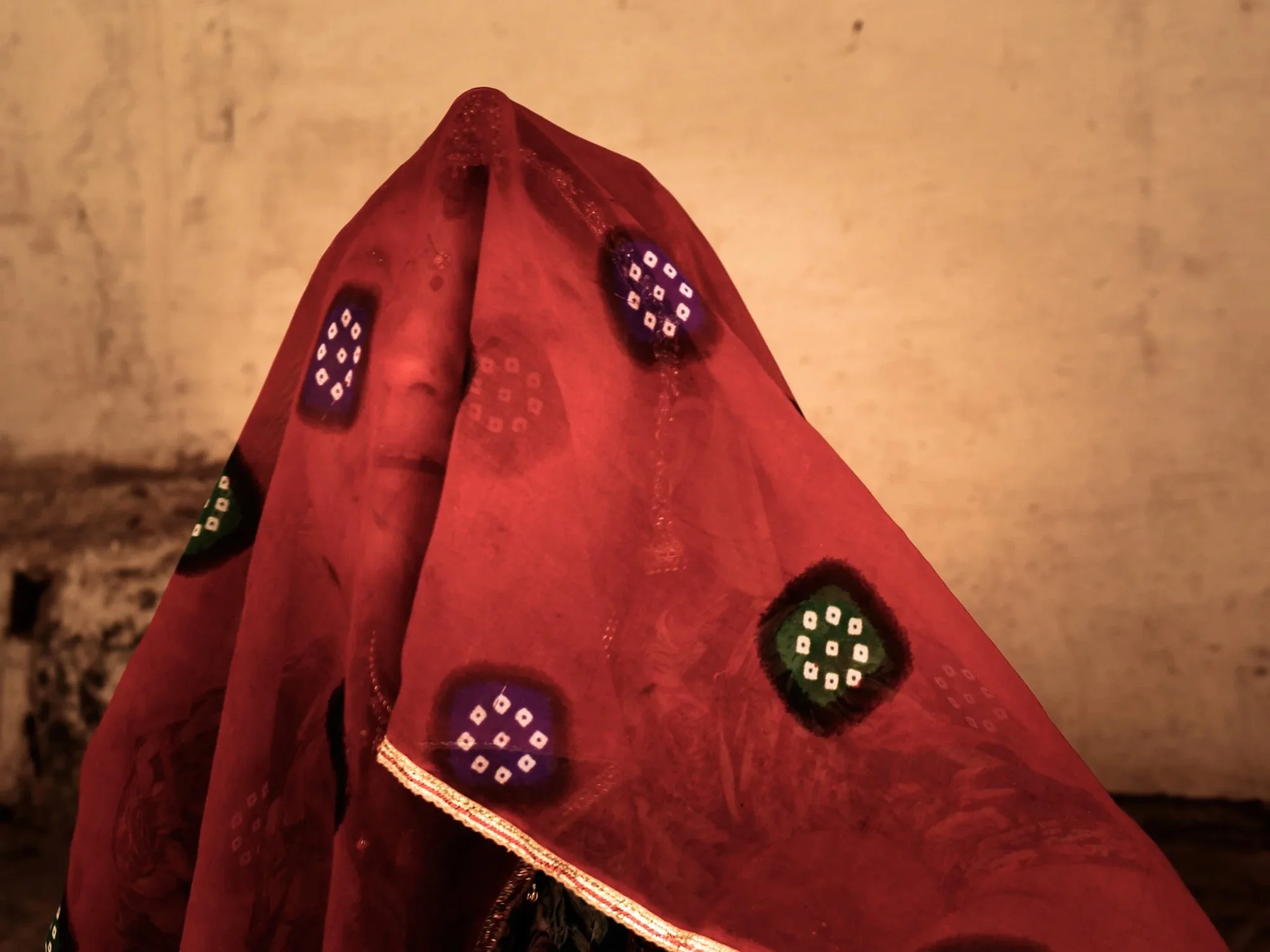 Close-up of a red fabric with colorful circular patterns, draped over an object.