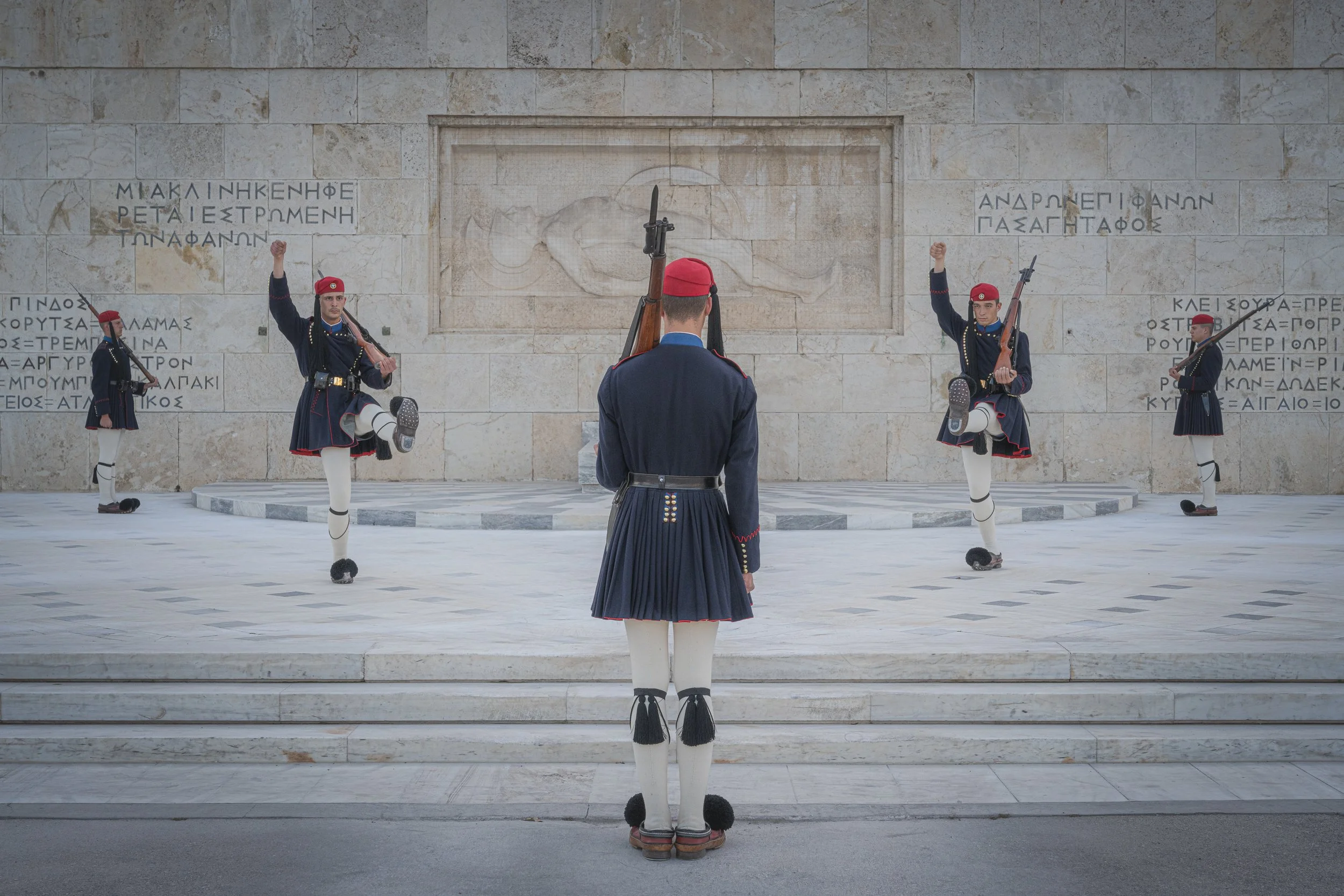 Greek soldiers in traditional uniform performing a ceremonial march at the Tomb of the Unknown Soldier in Athens.