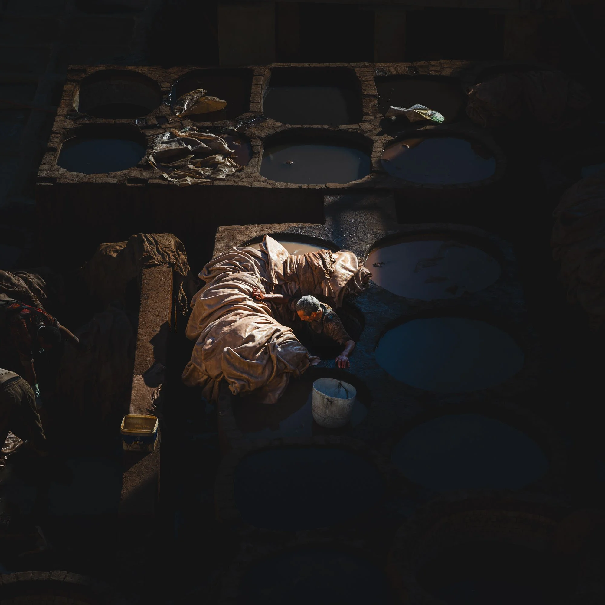 A high-contrast view of the Fes tanneries in Morocco where deep shadows create a grid of visual gaps, illustrating perceptual complexity and the architecture of absence