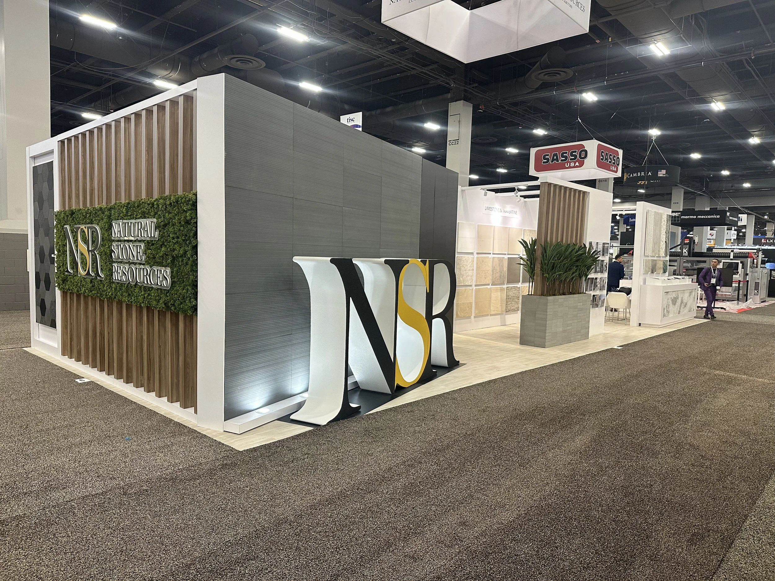Exhibition booth with the company logo 'Cipia' displayed on a large hanging sign, featuring a blue and white color scheme, cars, monitors, and informational displays at a trade show.