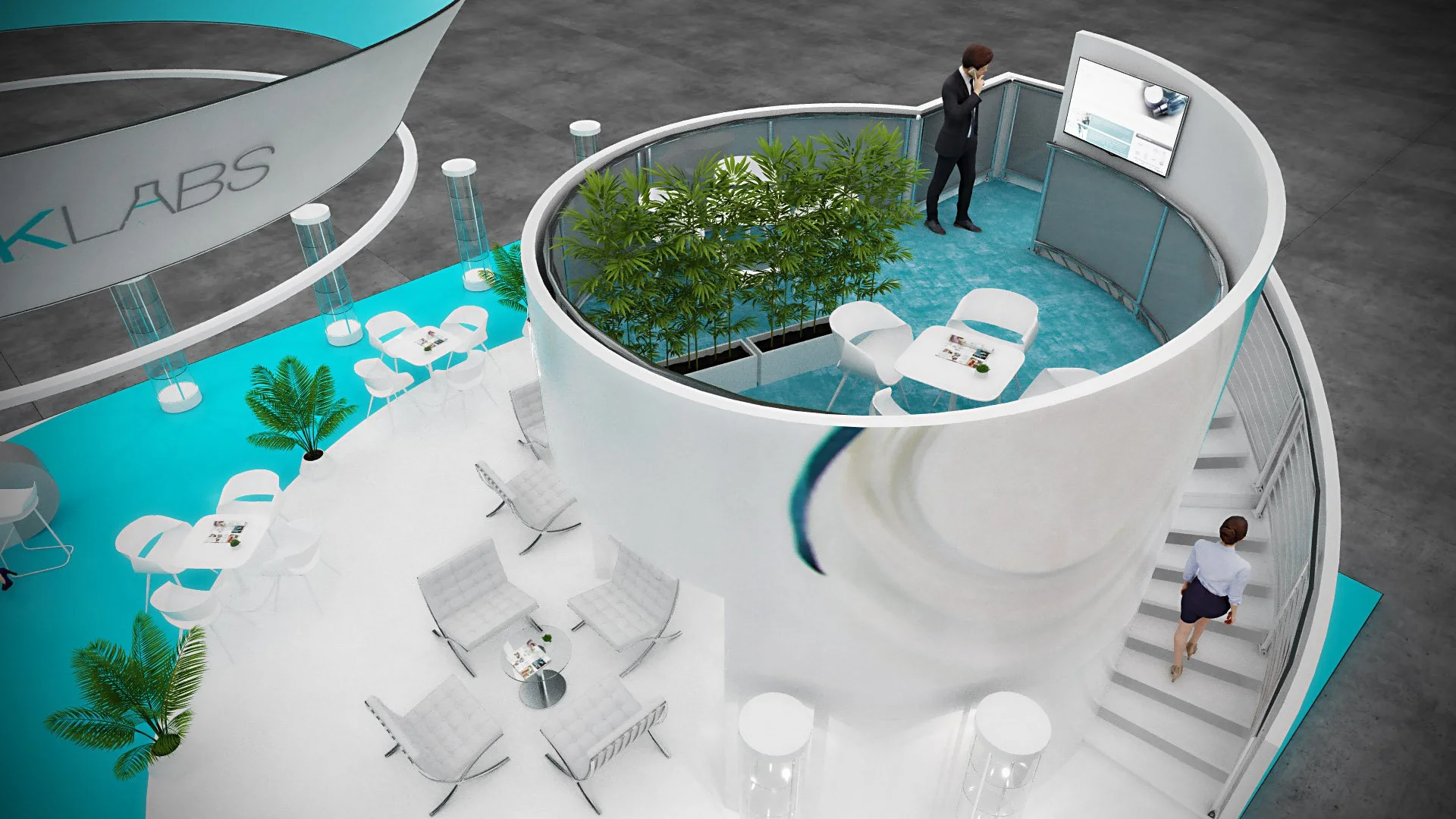 An indoor exhibition space with modern white furniture, green plants, and a circular glass-walled meeting area on a teal carpet. A woman is standing near a large screen, and a man is ascending stairs nearby. The area has a sign that reads 'KLABS'.