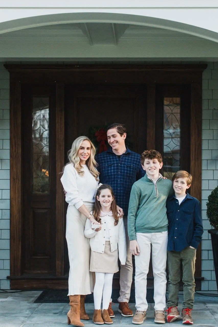 Family standing outside of their home, smiling together during winter holidays