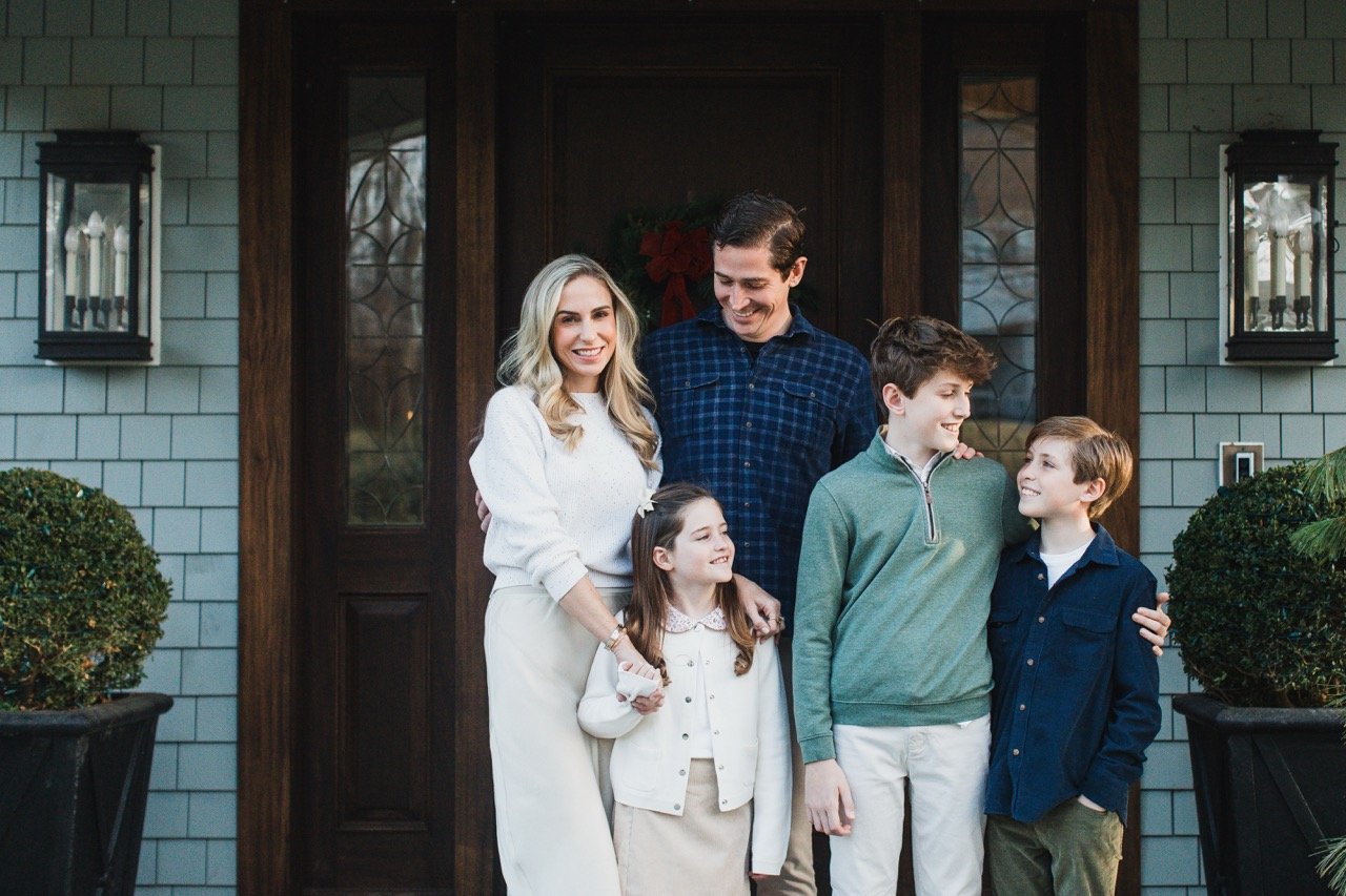 A family of six standing in front of a house, smiling and enjoying each other's company during a festive occasion