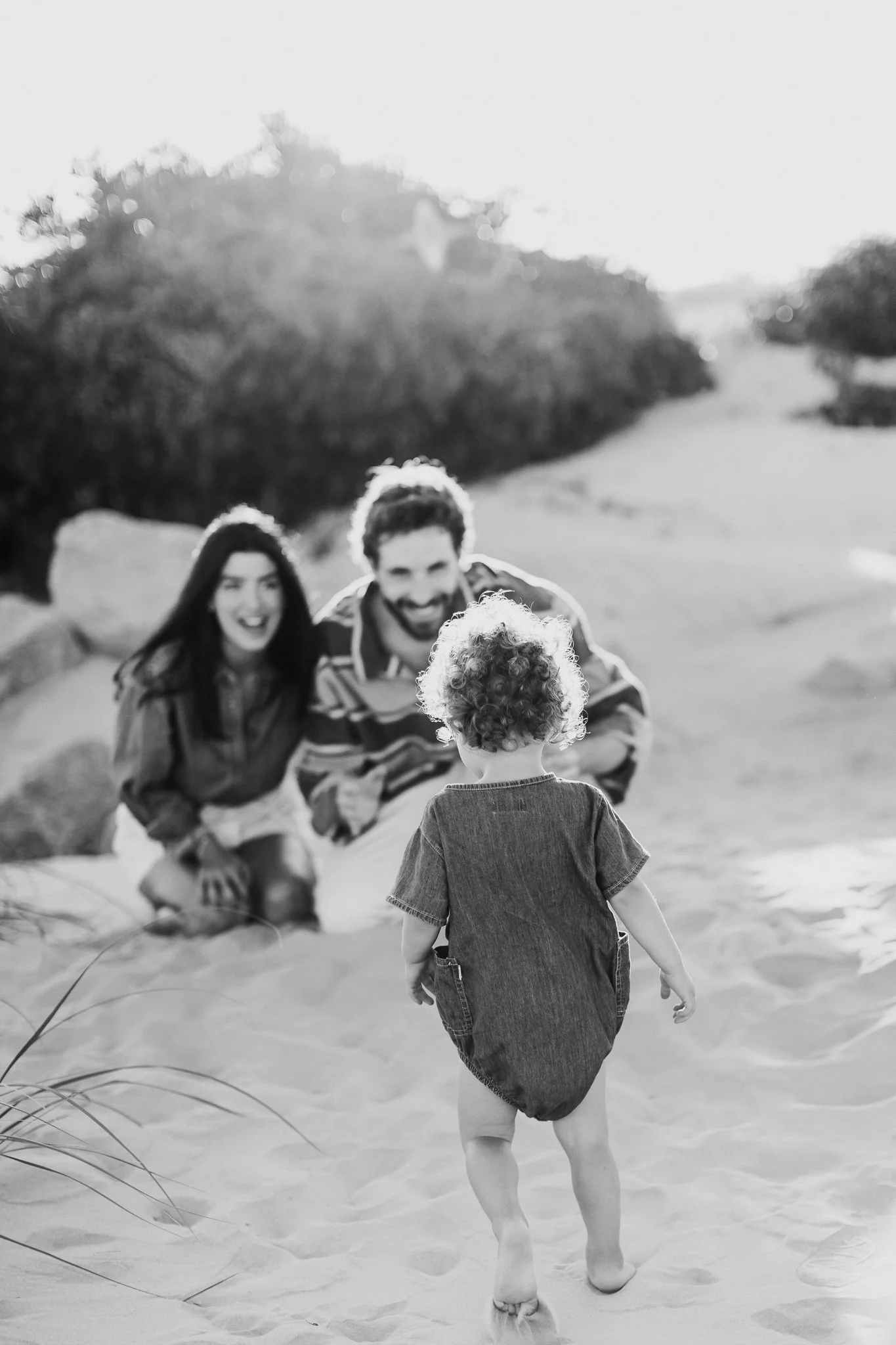 Joyful parents with young children playing on East Hampton beach during family photo session