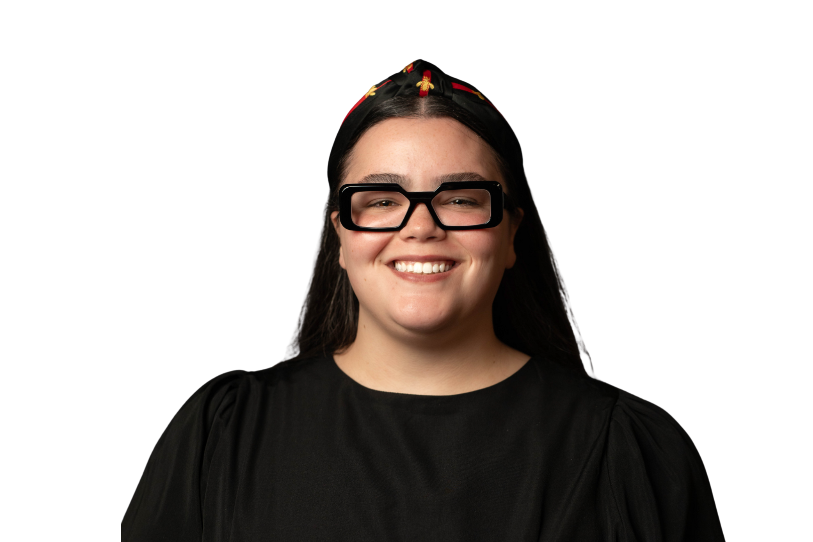 Smiling woman with long hair, wearing a yellow headband and black polka dot mesh top, arms crossed.