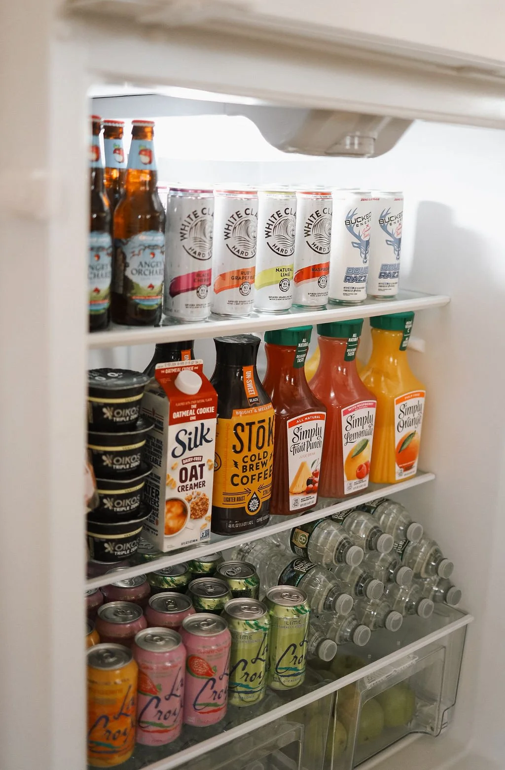 a fully stocked fridge with water, juice, coffee and alcohol in it