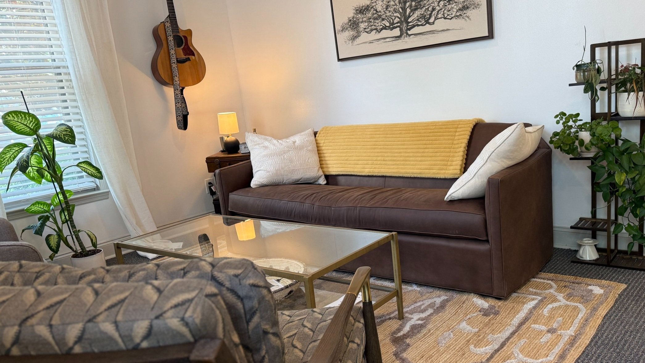 Modern room with brown leather sofa, guitar, and green houseplants in Murfreesboro, Tn | Couples Therapy & Family Counseling | Clarity Therapy Murfreesboro