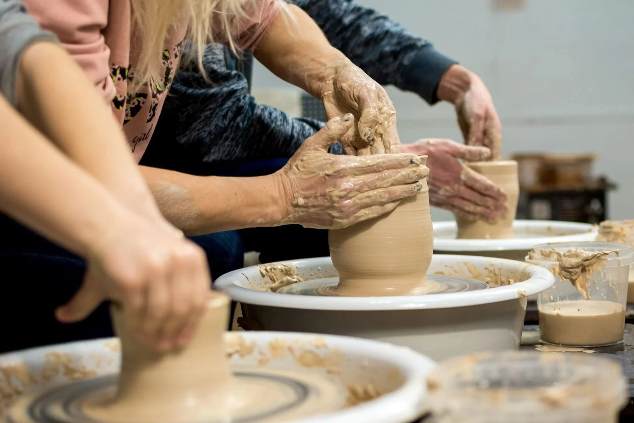 people creating pottery on a wheel