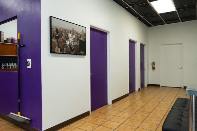 nterior of a modern barber shop xternalstudio located in clovis CA Interior hallway with purple doors and white walls, a motivational poster saying "Today or Never," and tiled flooring.
