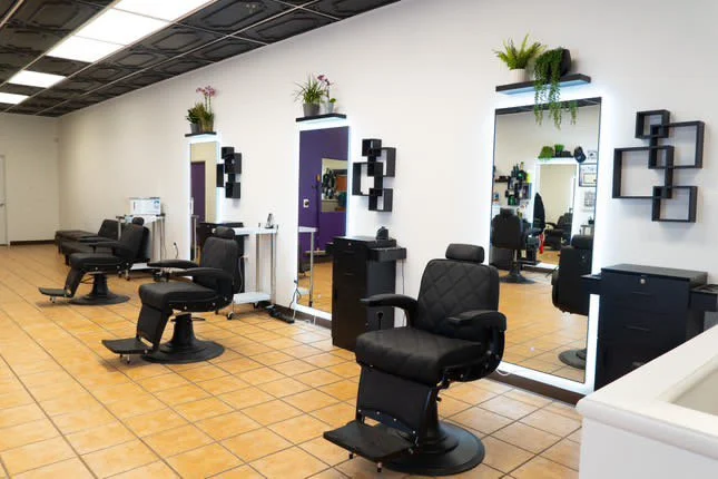 nterior of a modern barber shop xternalstudio located in clovis CA illuminated mirrors, and decorative plants on the walls. The floor is tiled, with a clean and organized appearance.
