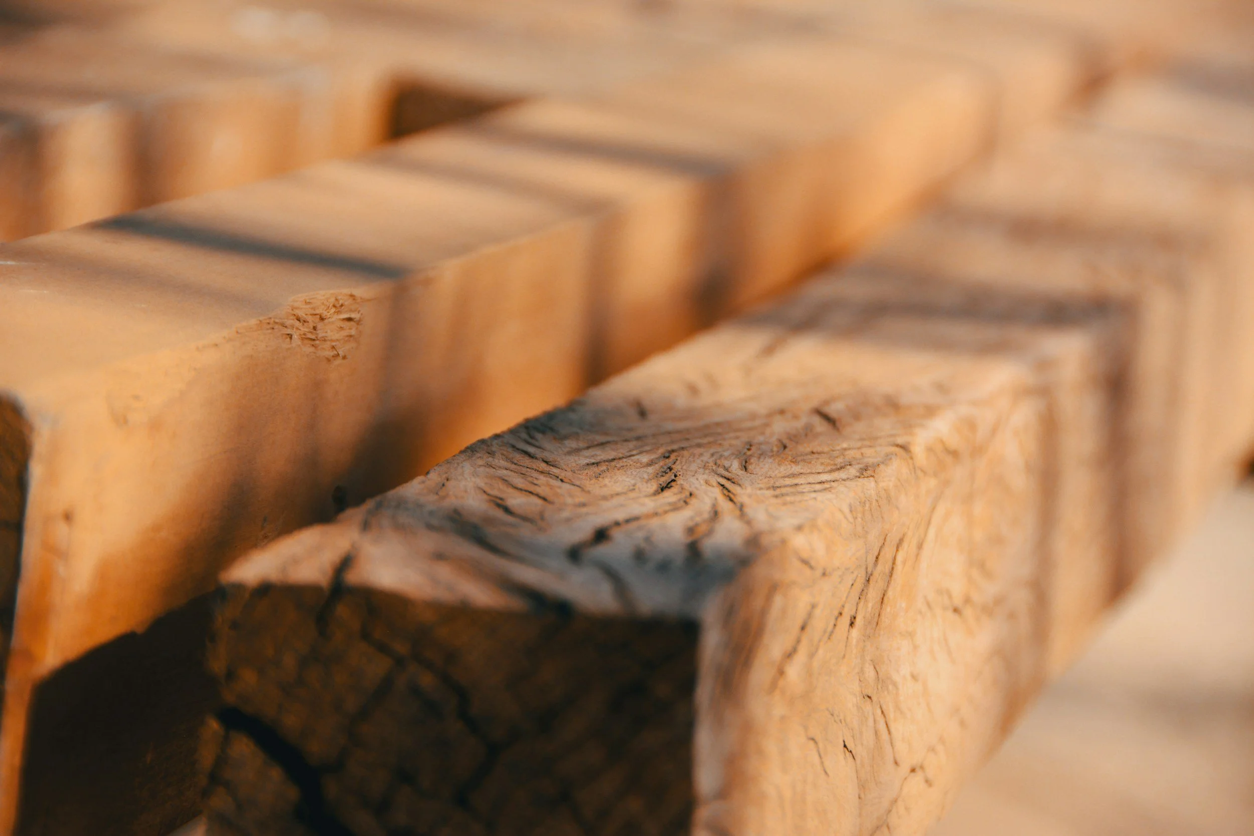 Close-up view of stacked pieces of aged, textured wood showing natural grain and cracks.
